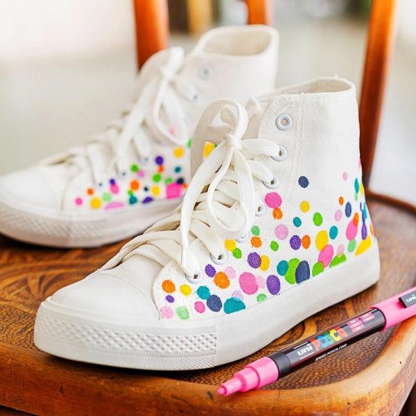 White sneakers decorated with colorful, overlapping dots. A marker pen rests nearby.