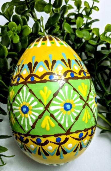 A colorfully-decorated egg in geometric designs of green, brown, and yellow.