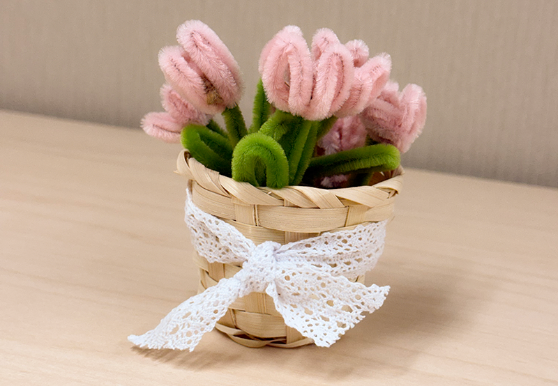 A craft of a cute basket of decorative tulips made of pipe cleaners.