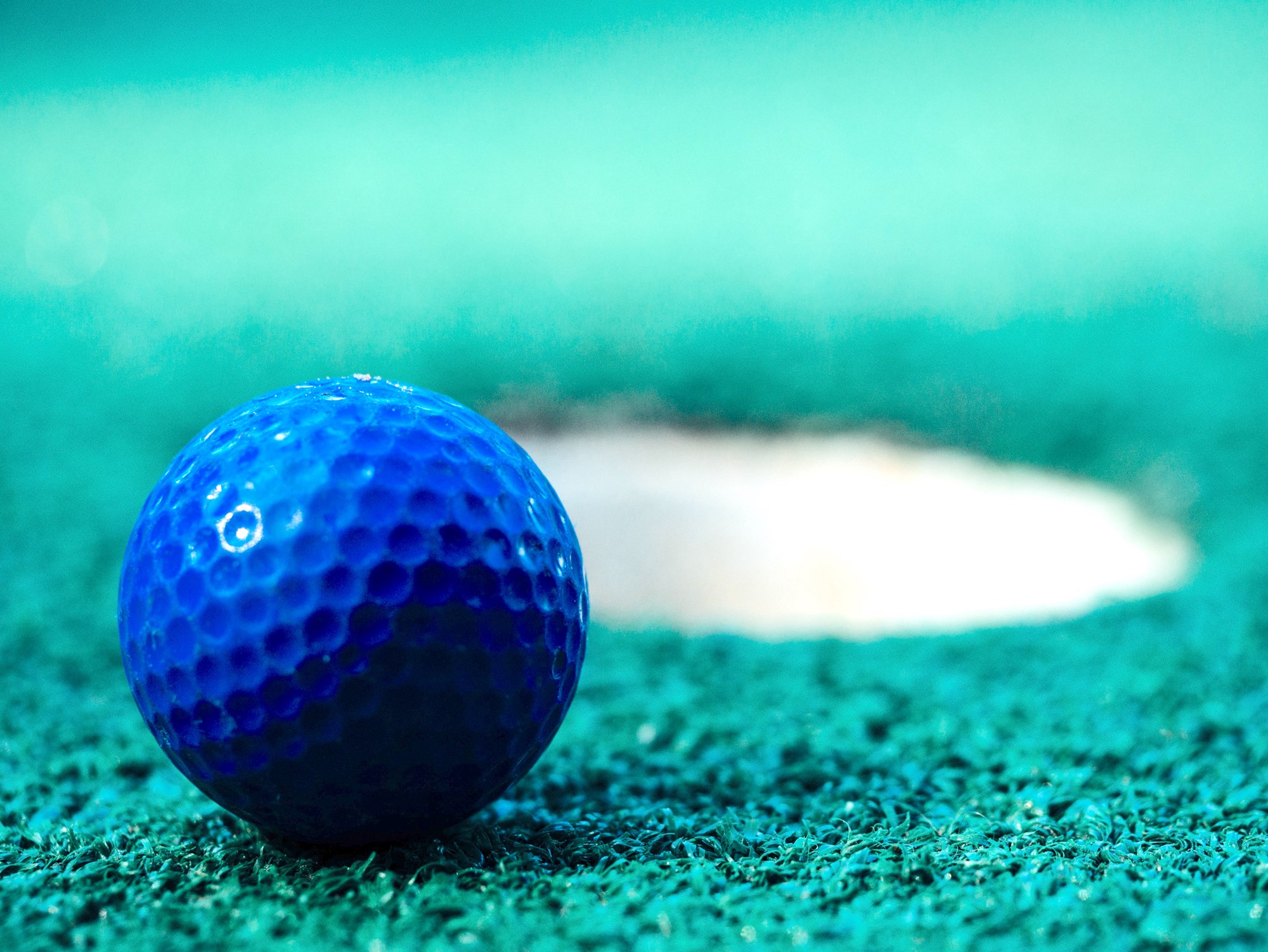 Blue Golf Ball Next to Hole