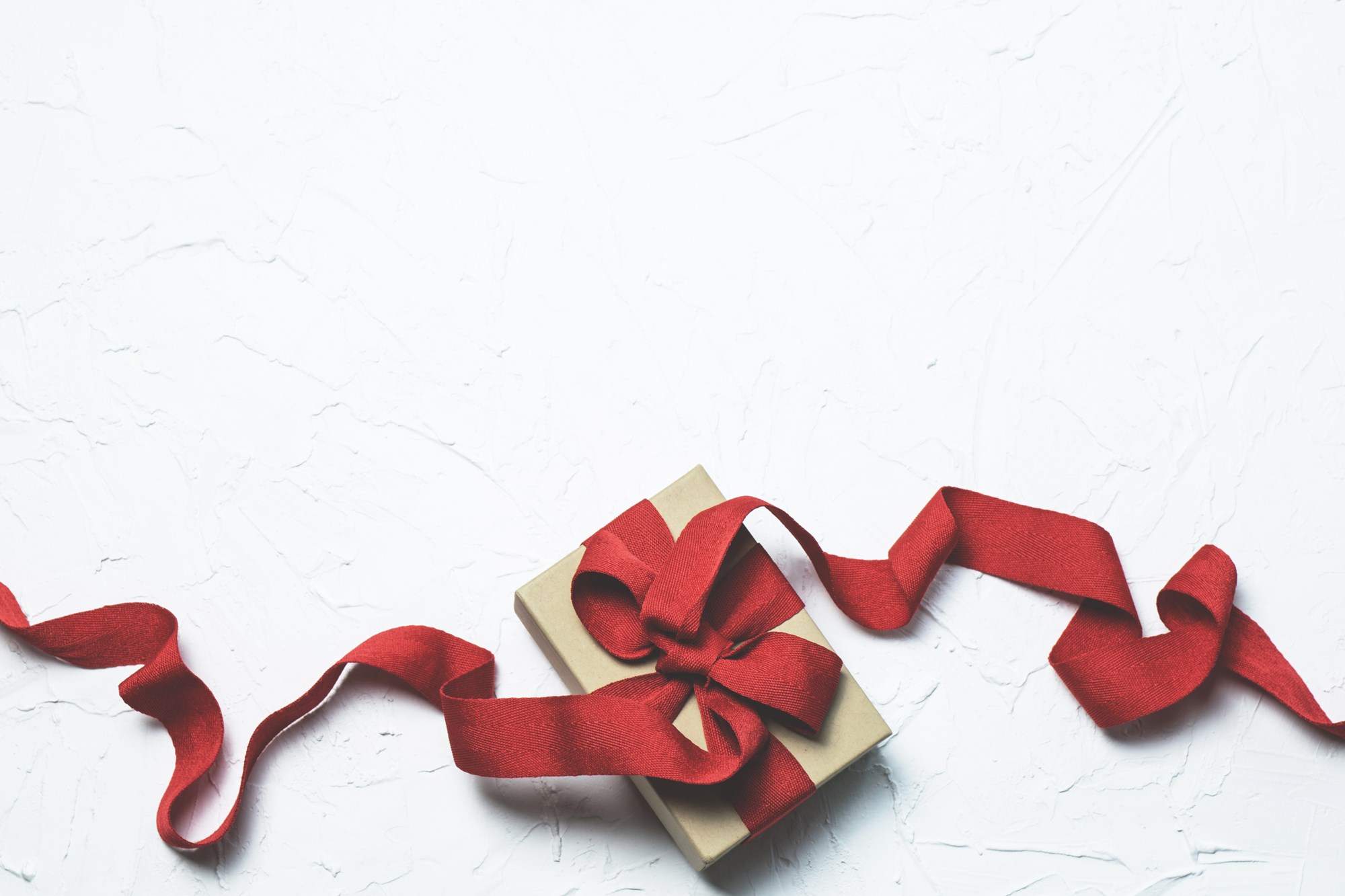 Box wrapped in red ribbon on white background
