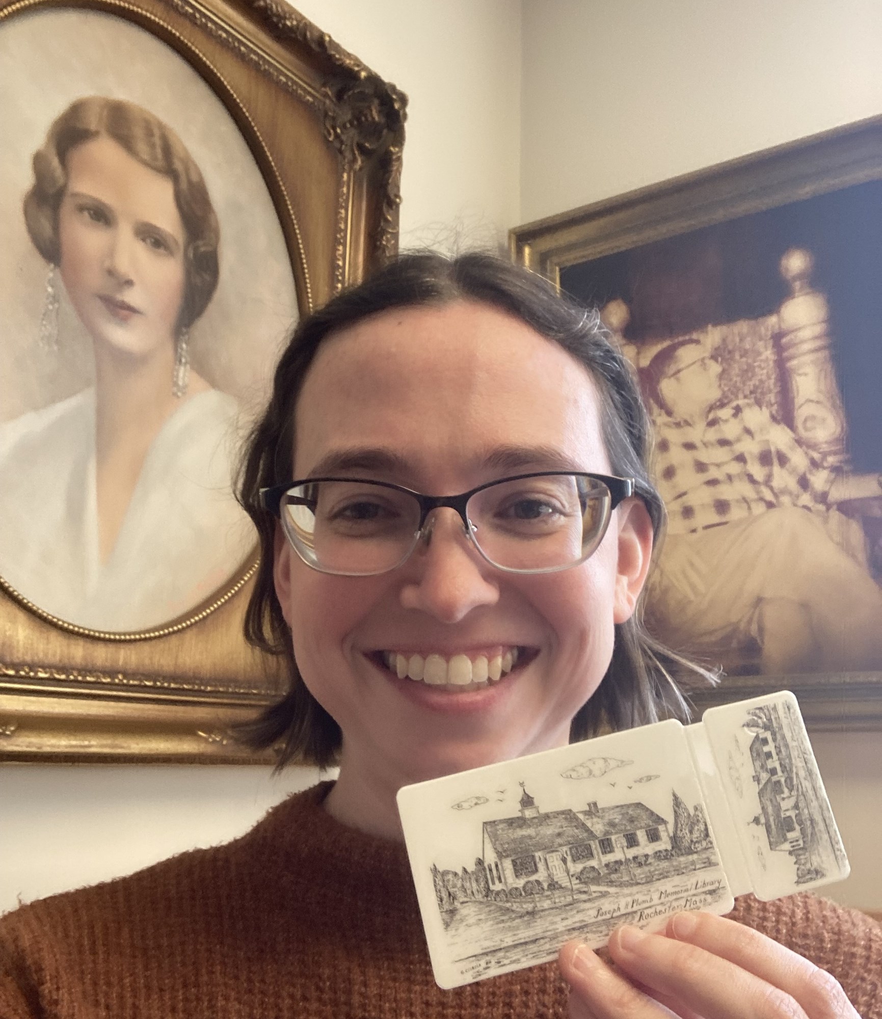 Library Director with 50th Anniversary Library card in front of portraits of Mr. and Mrs. Plumb