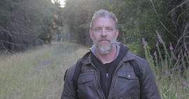 Photo of Ronnie LeBlanc standing in a grassy path, with trees on the edges