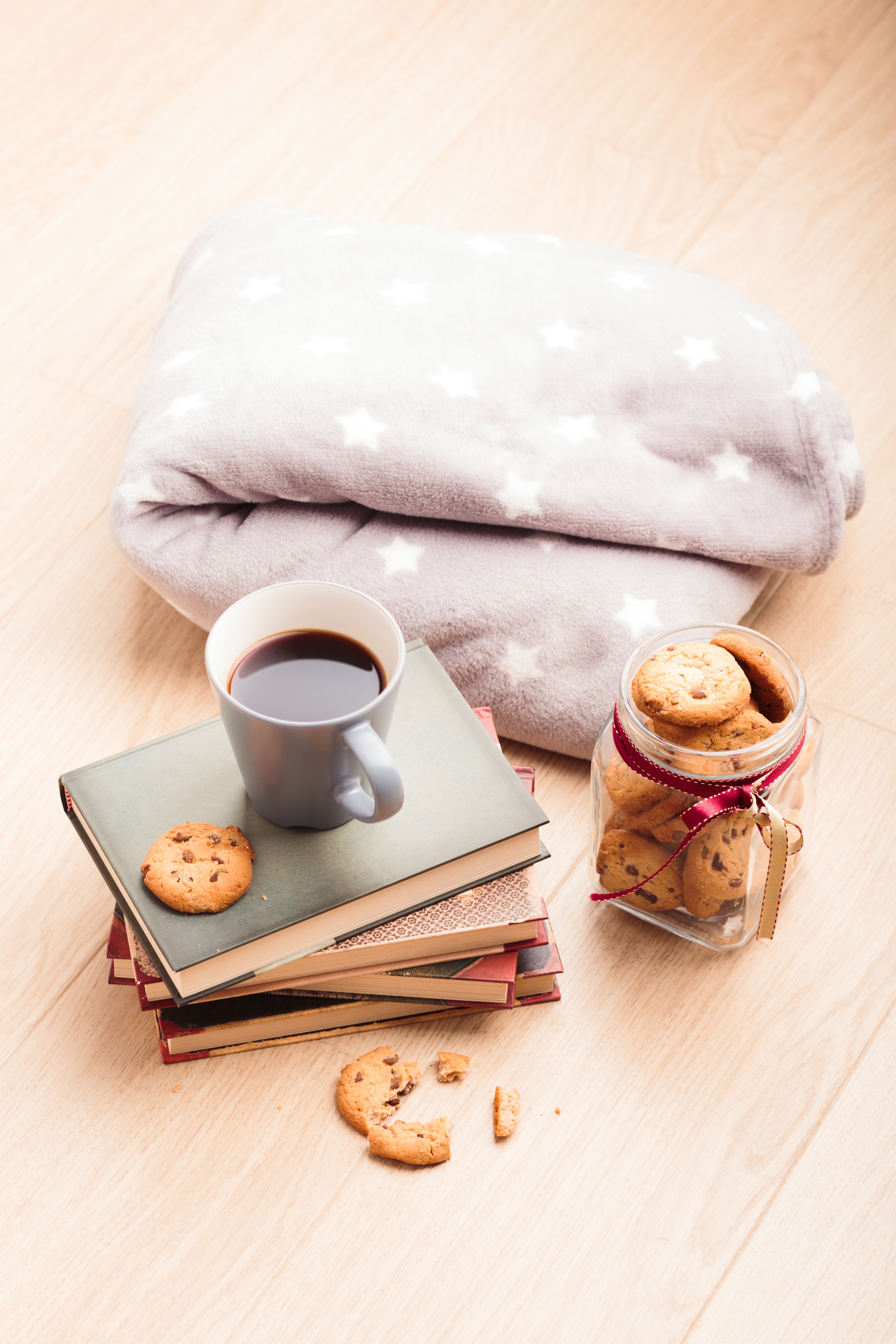 Stack of Books with Cup of Coffee and Cookies on Wooden Floor