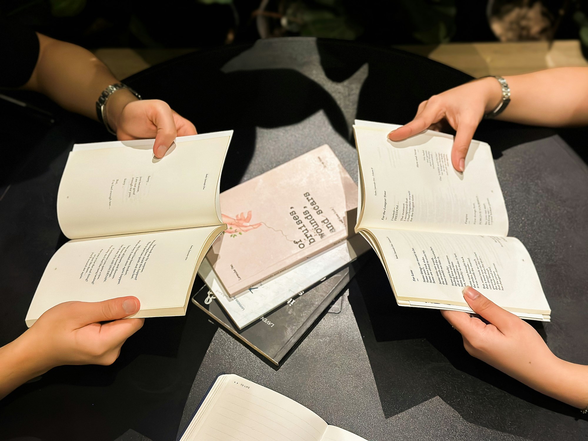 Hands Holding Open Books Around a Table