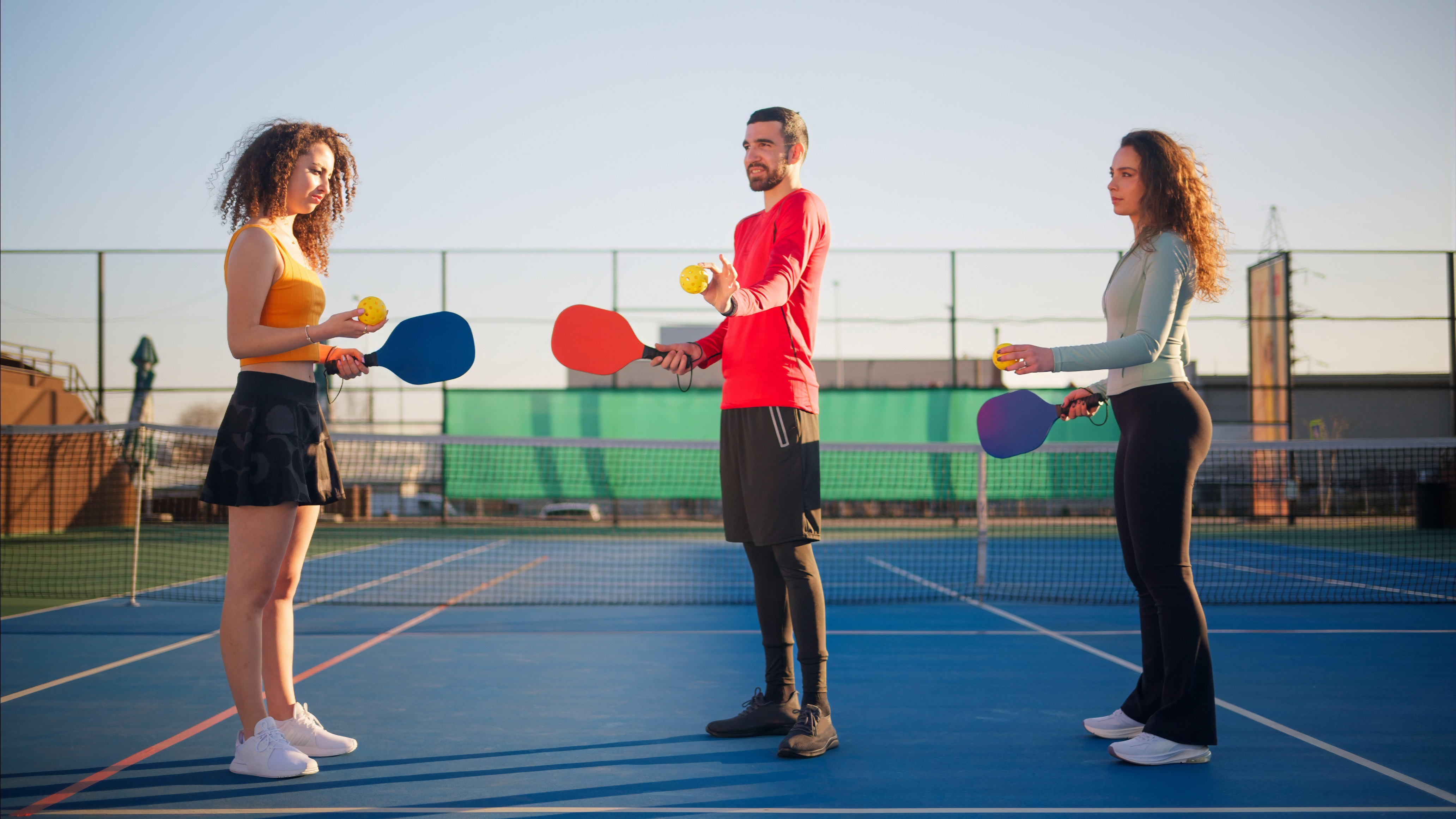 3 adults playing pickleball