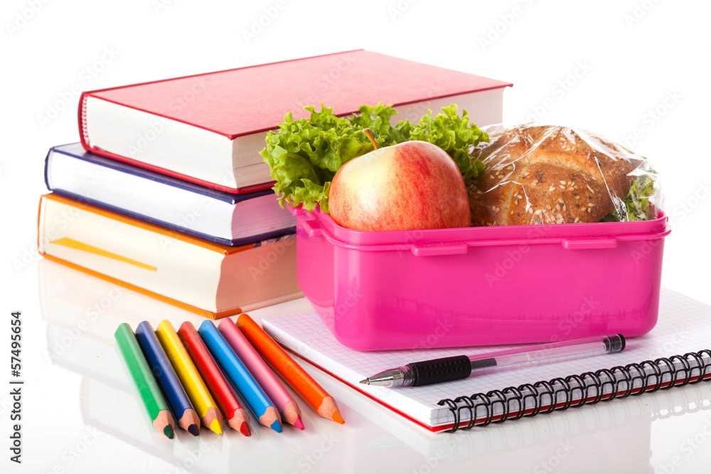 Stack of books, lunch box, notebook and colored pencils