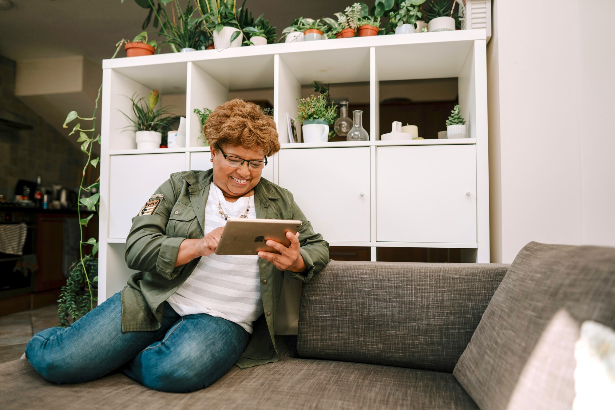 A Woman Sitting on a Couch Looking at a Tablet