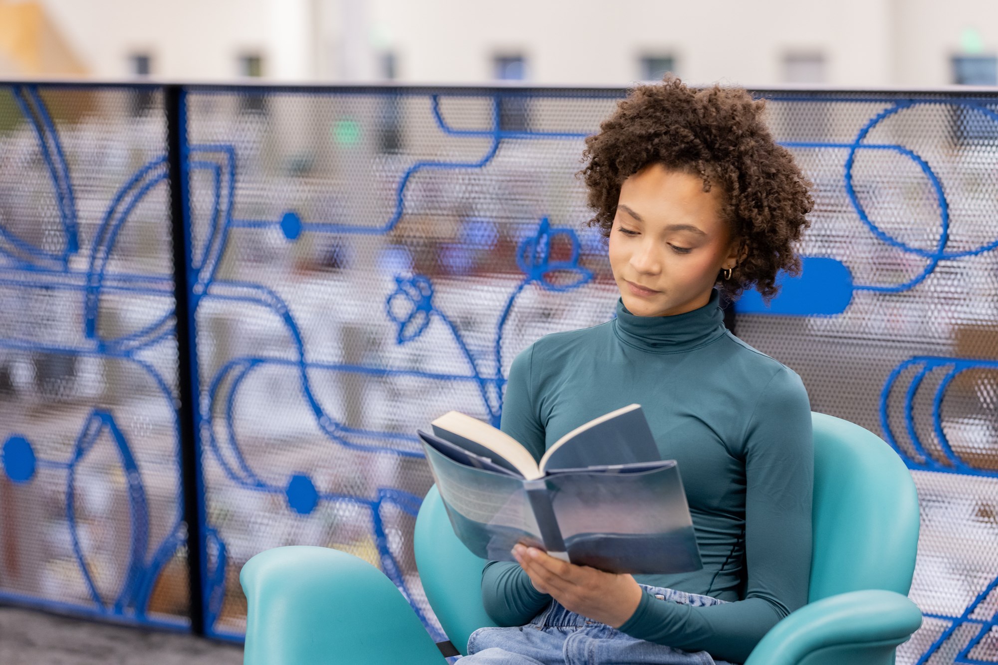 Teenage Girl Reads Book in Modern Library