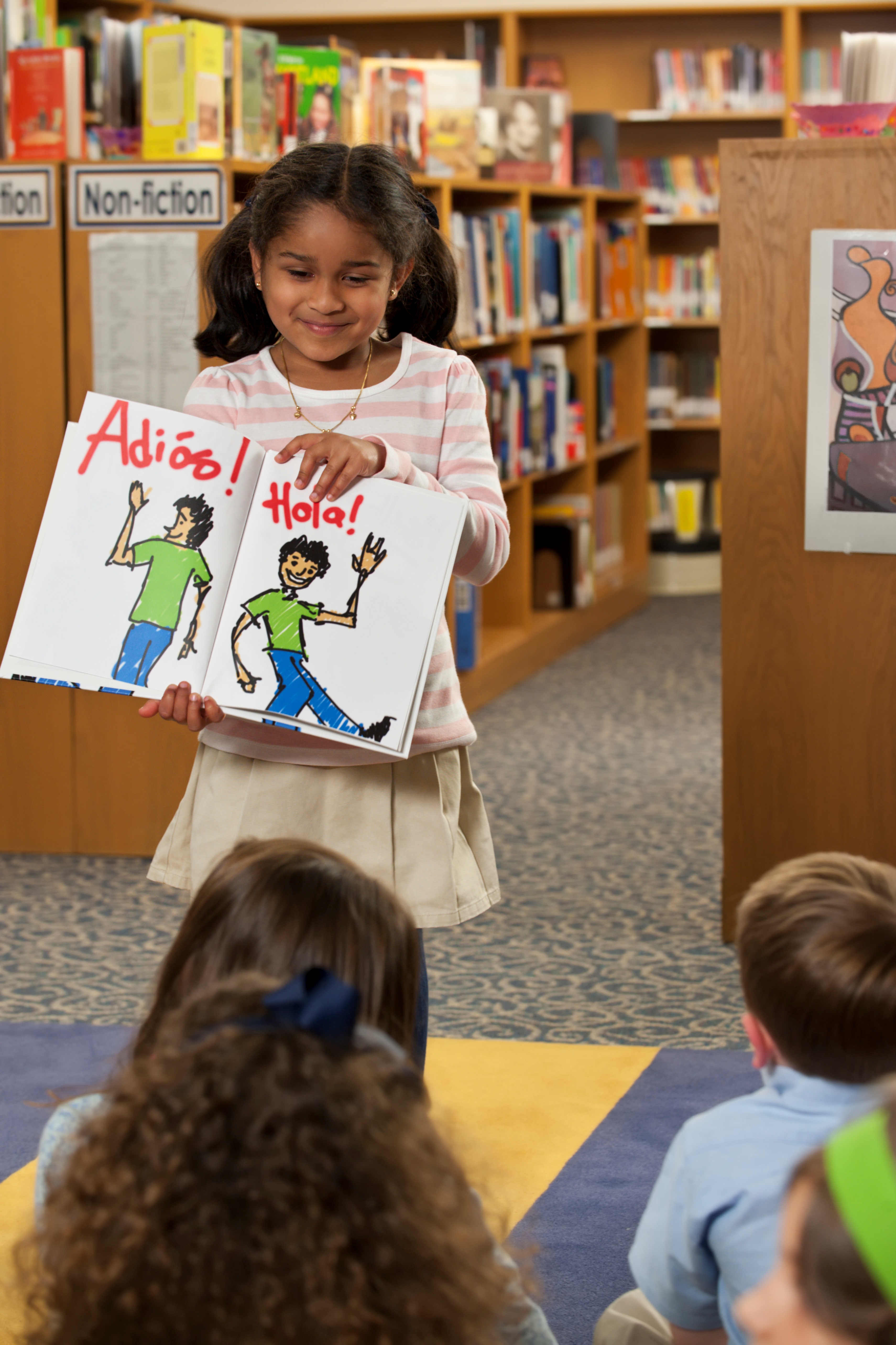 Little Girl Showing Spanish Book to Classmates in Library