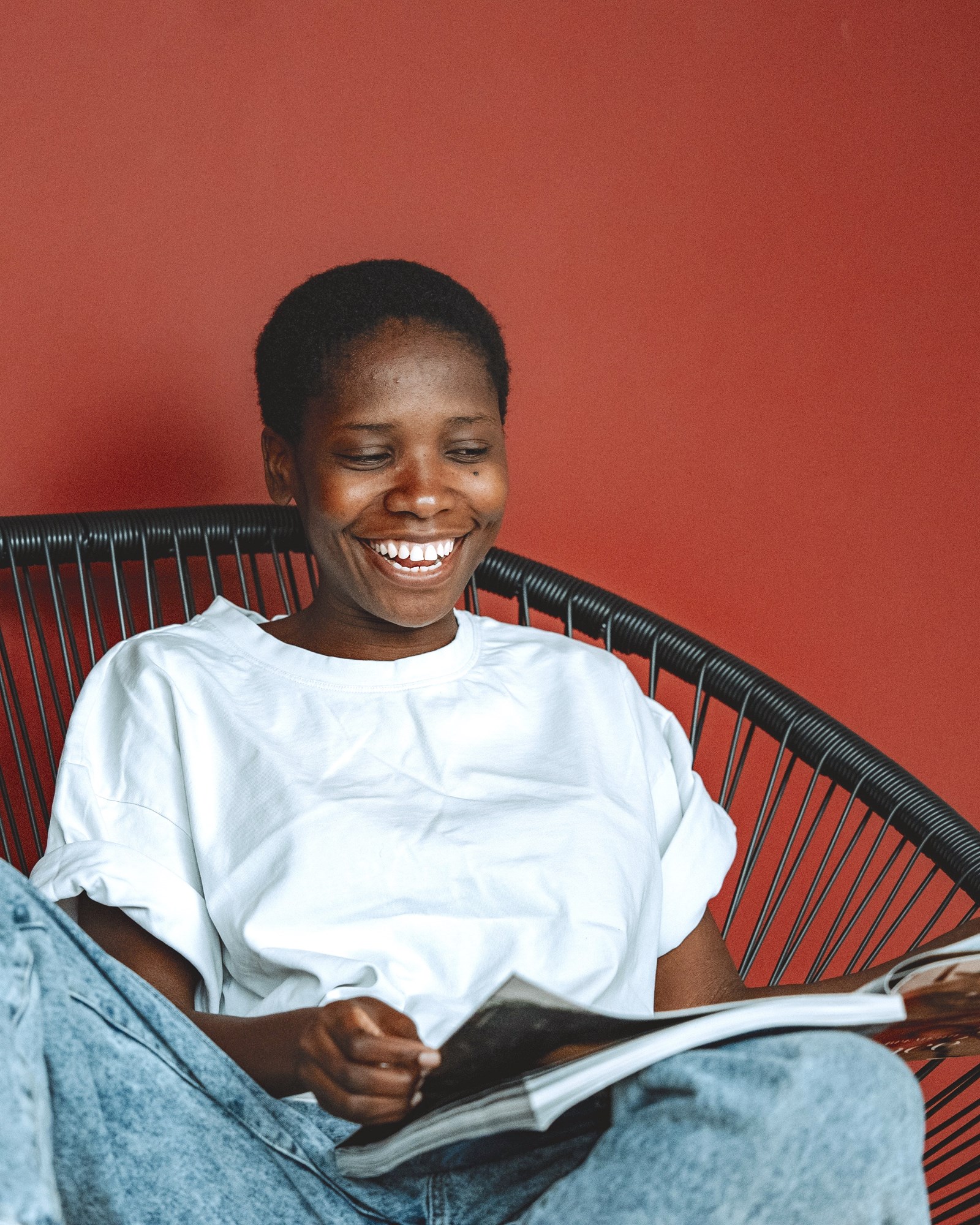 Happy Woman Reading a Magazine Against Red Wall
