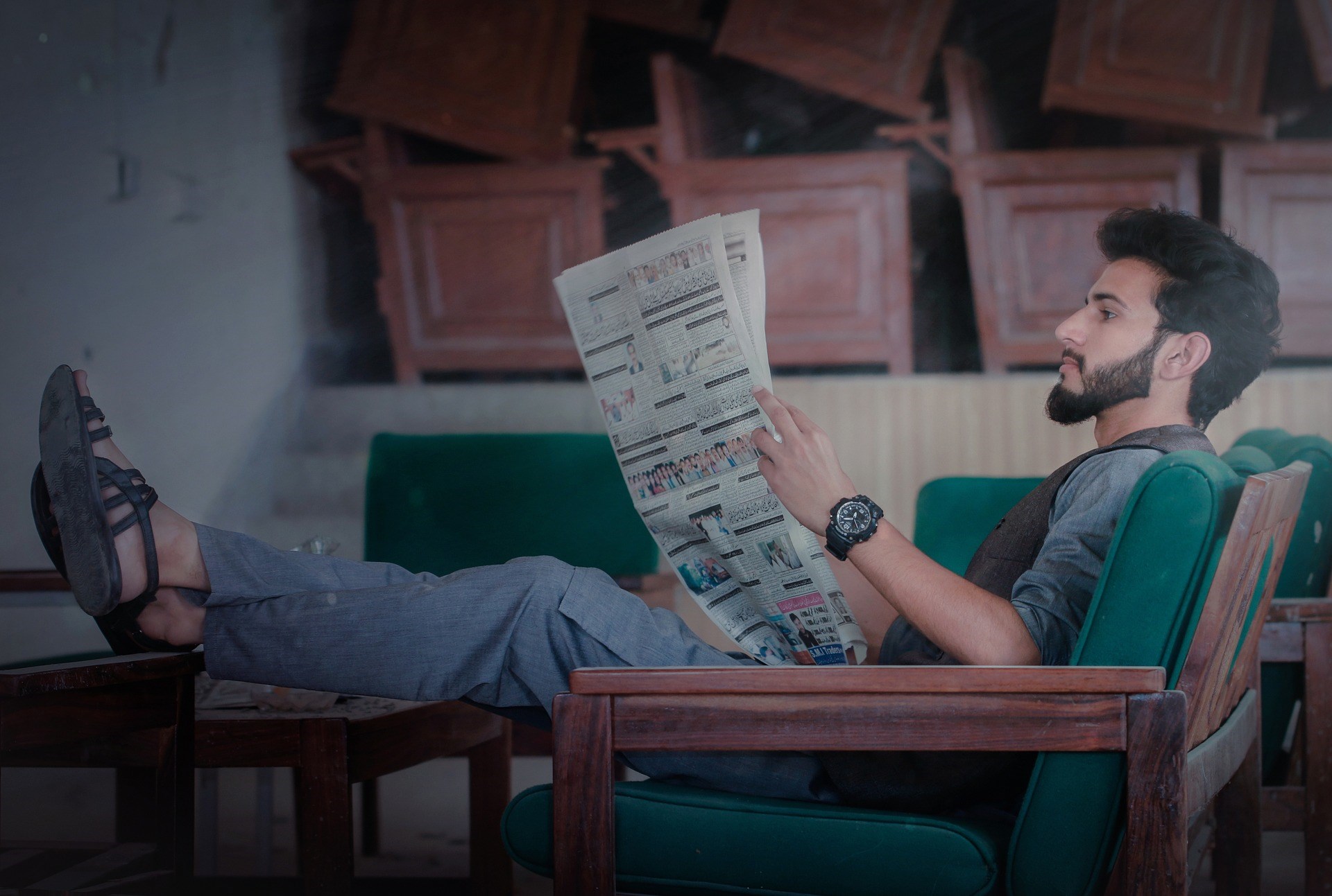 A Man Sitting on the Chair and Reading a Newspaper