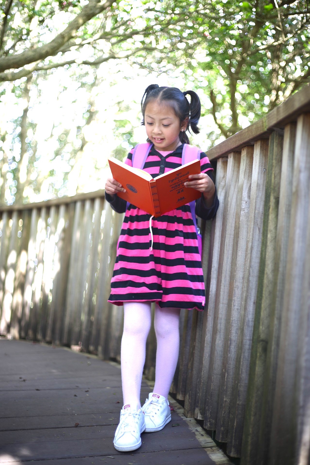 Young Girl Reading an Open Book While Walking at Outdoors