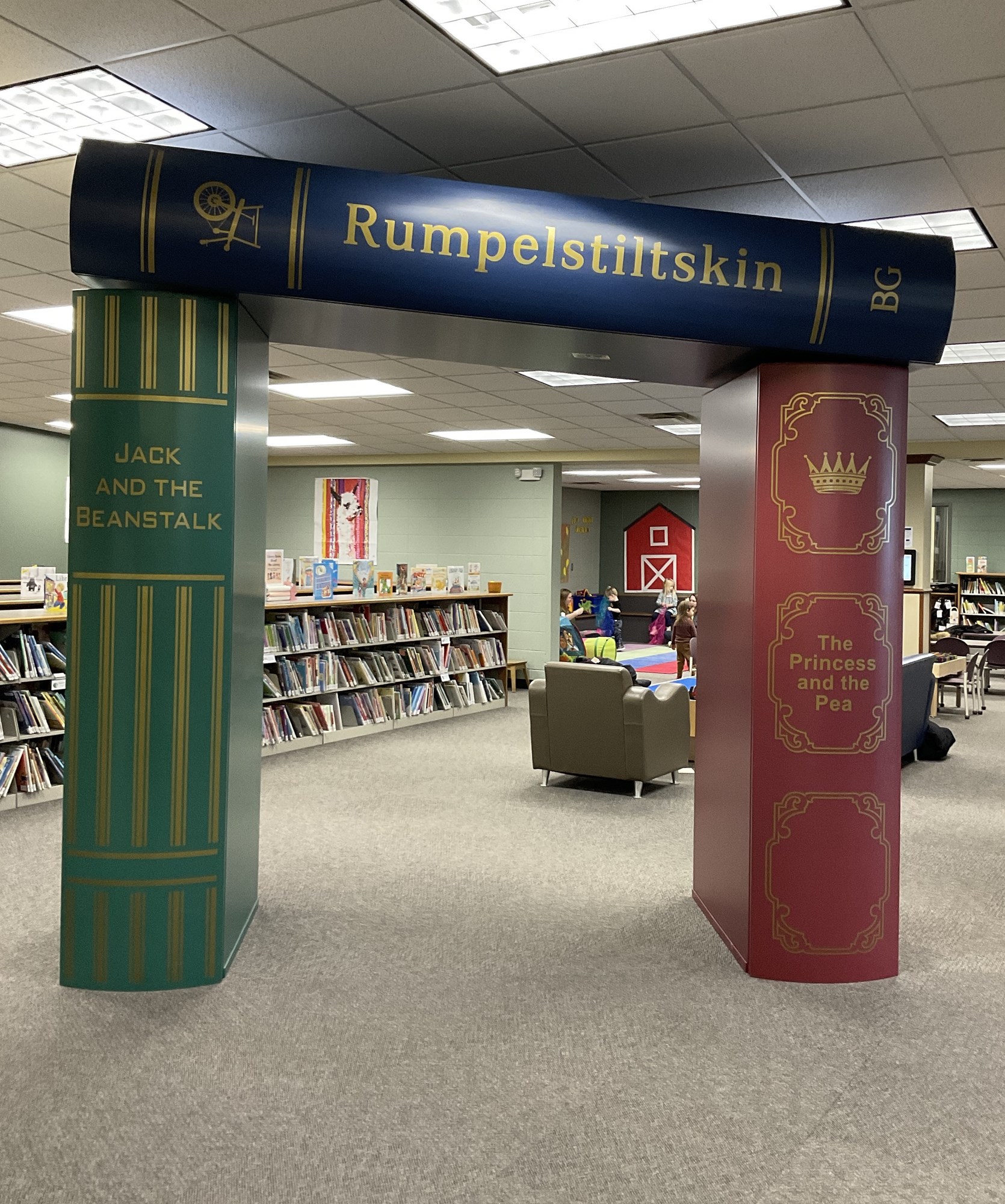 Photo of entrance to the children's area in the library. 3 large books form a doorway.