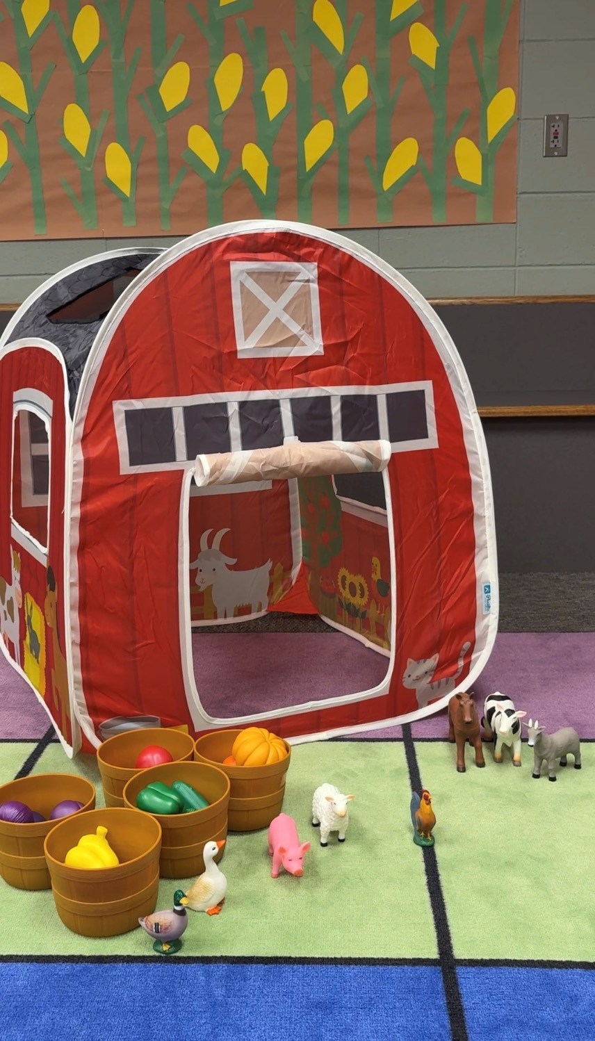 Photo of play tent barn, animals and vegetables in the children's area of the library.