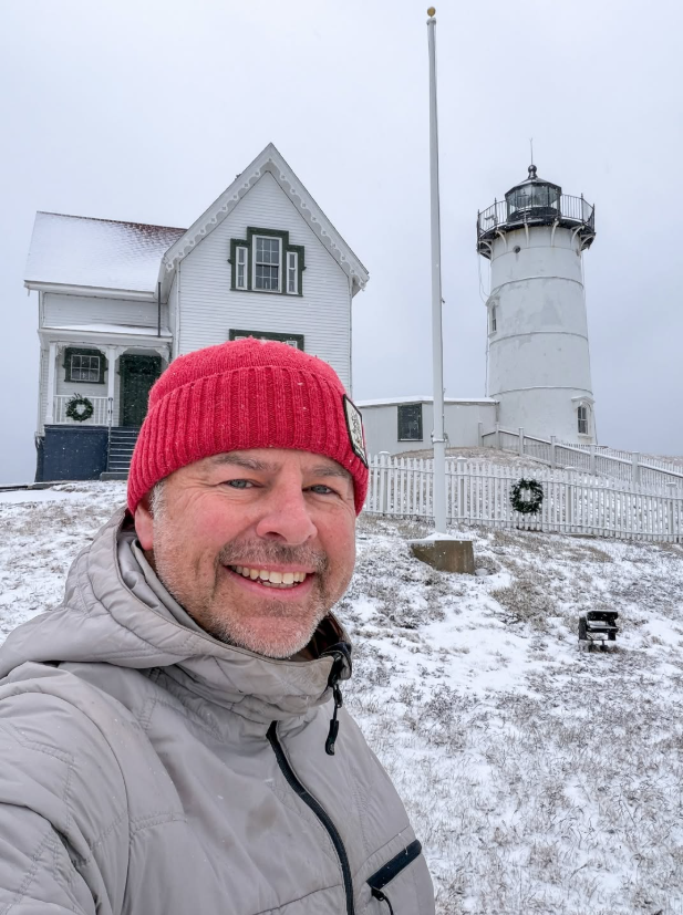 Matt in front of a wintry Nubble lighthouse smiling 