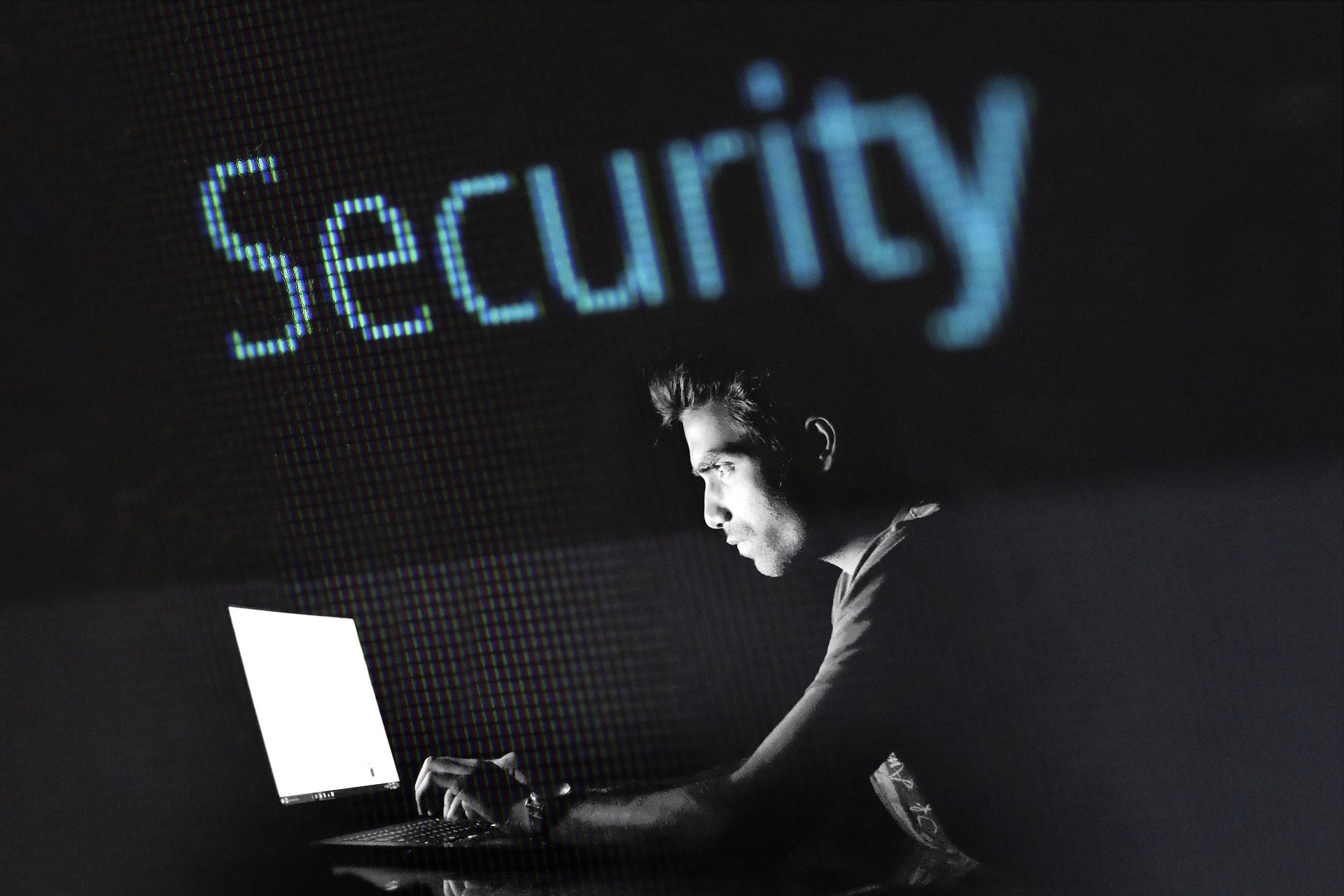 man looking at laptop with word security in the background