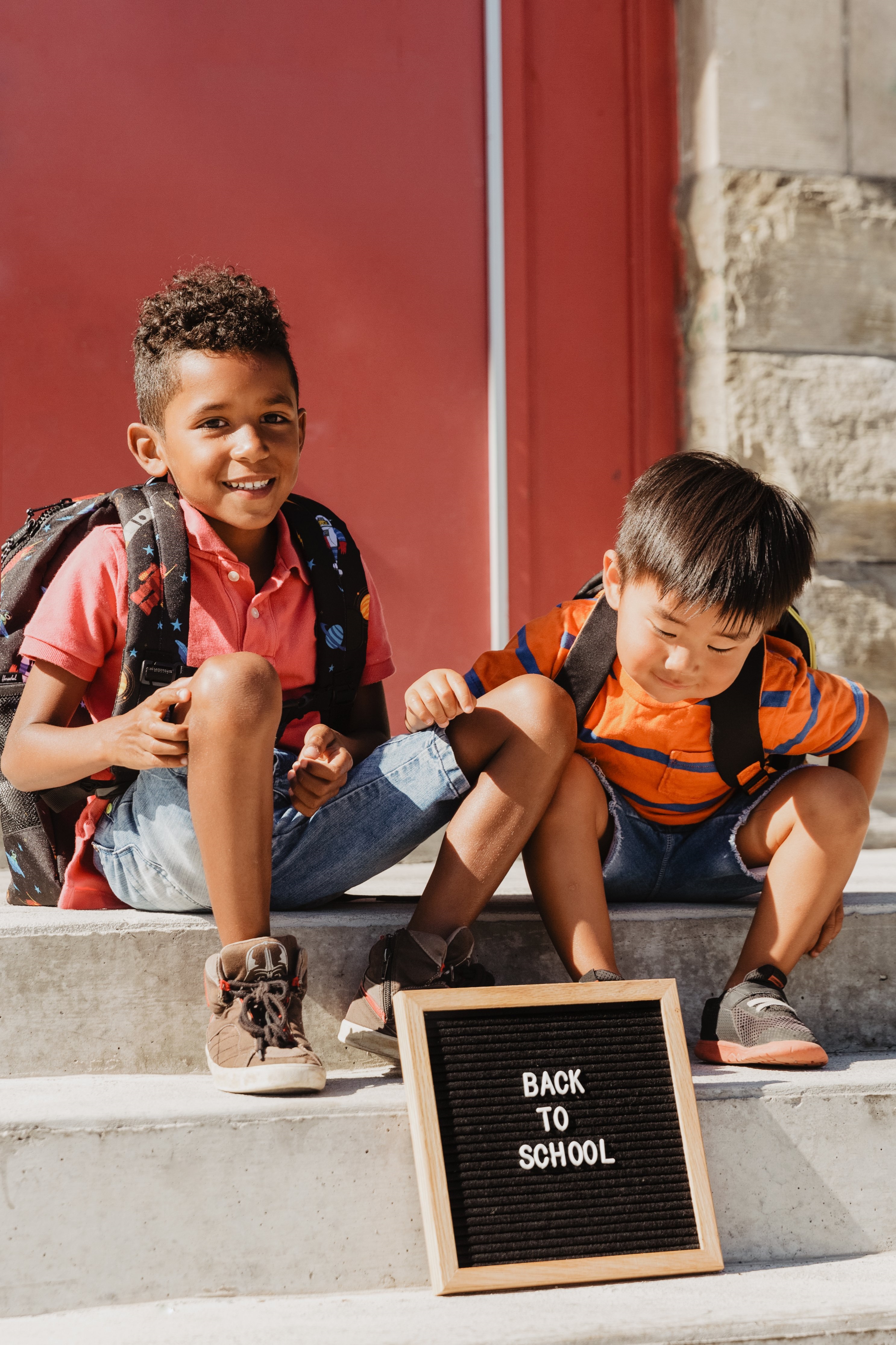 Kids Sitting on School Steps with Back to School Sign