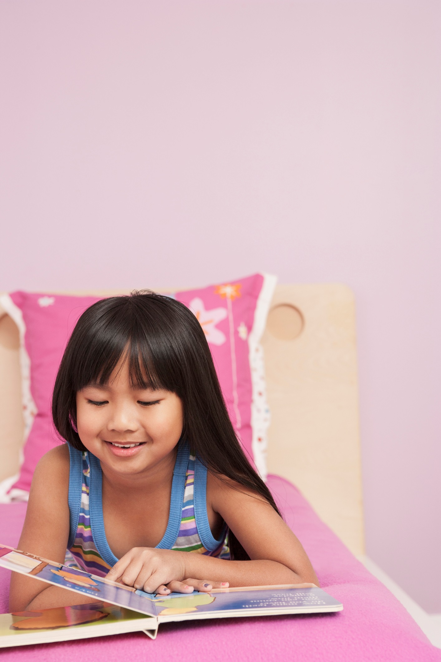 Girl Laying on Pink Bed Reading a Book