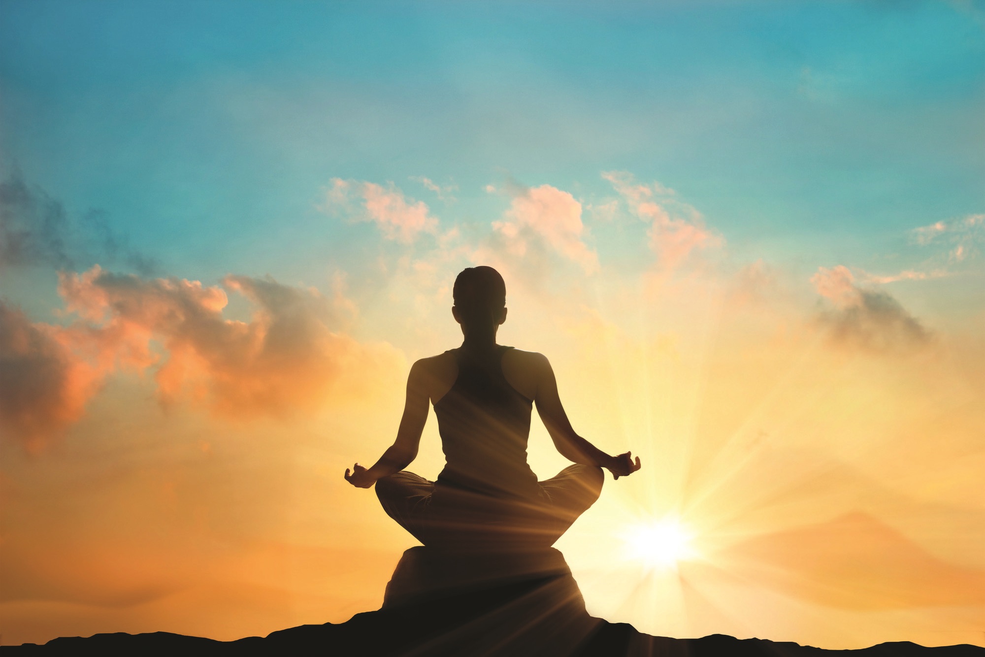 Person meditating during sunrise