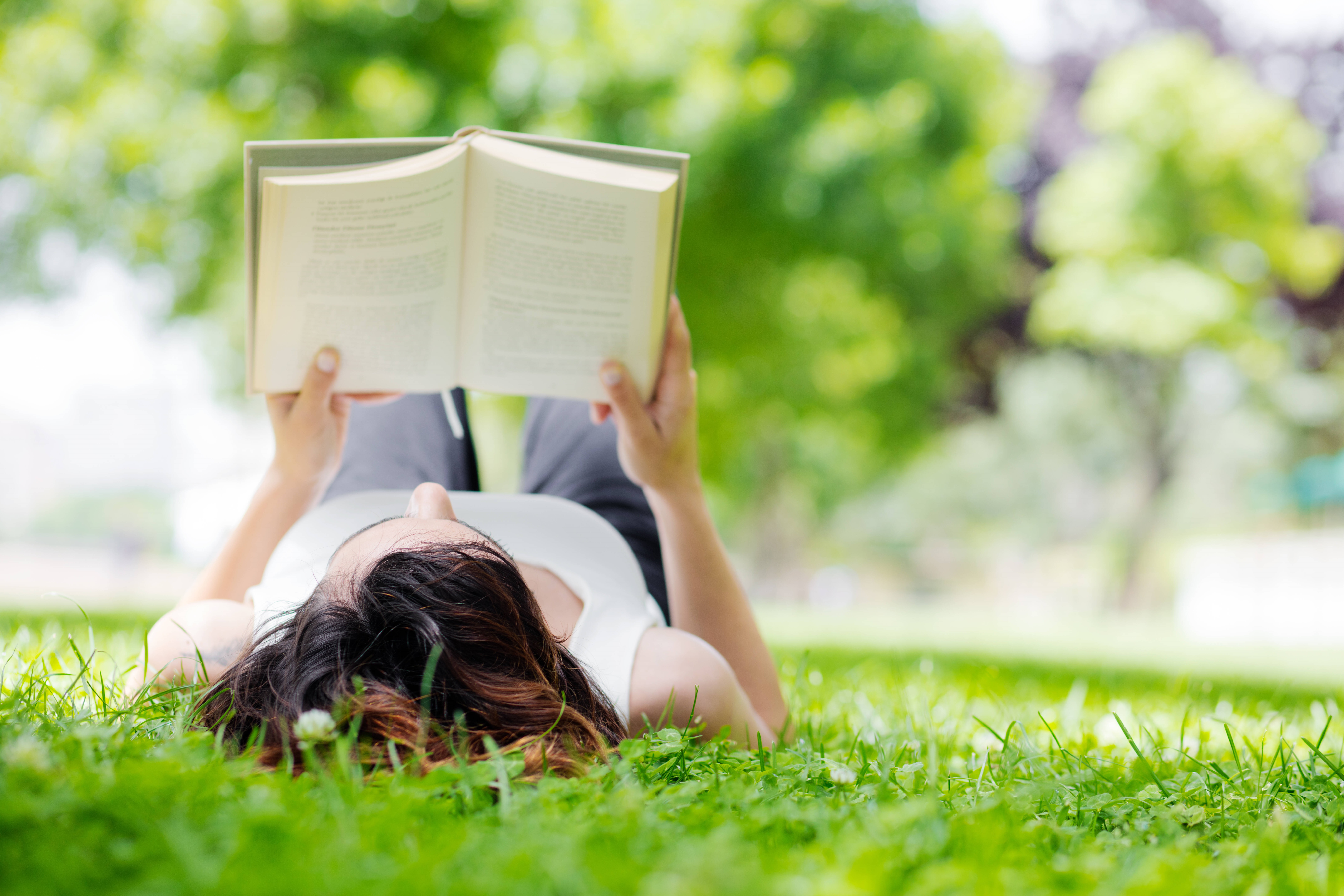 Woman Lying on Grass and Reading a Book