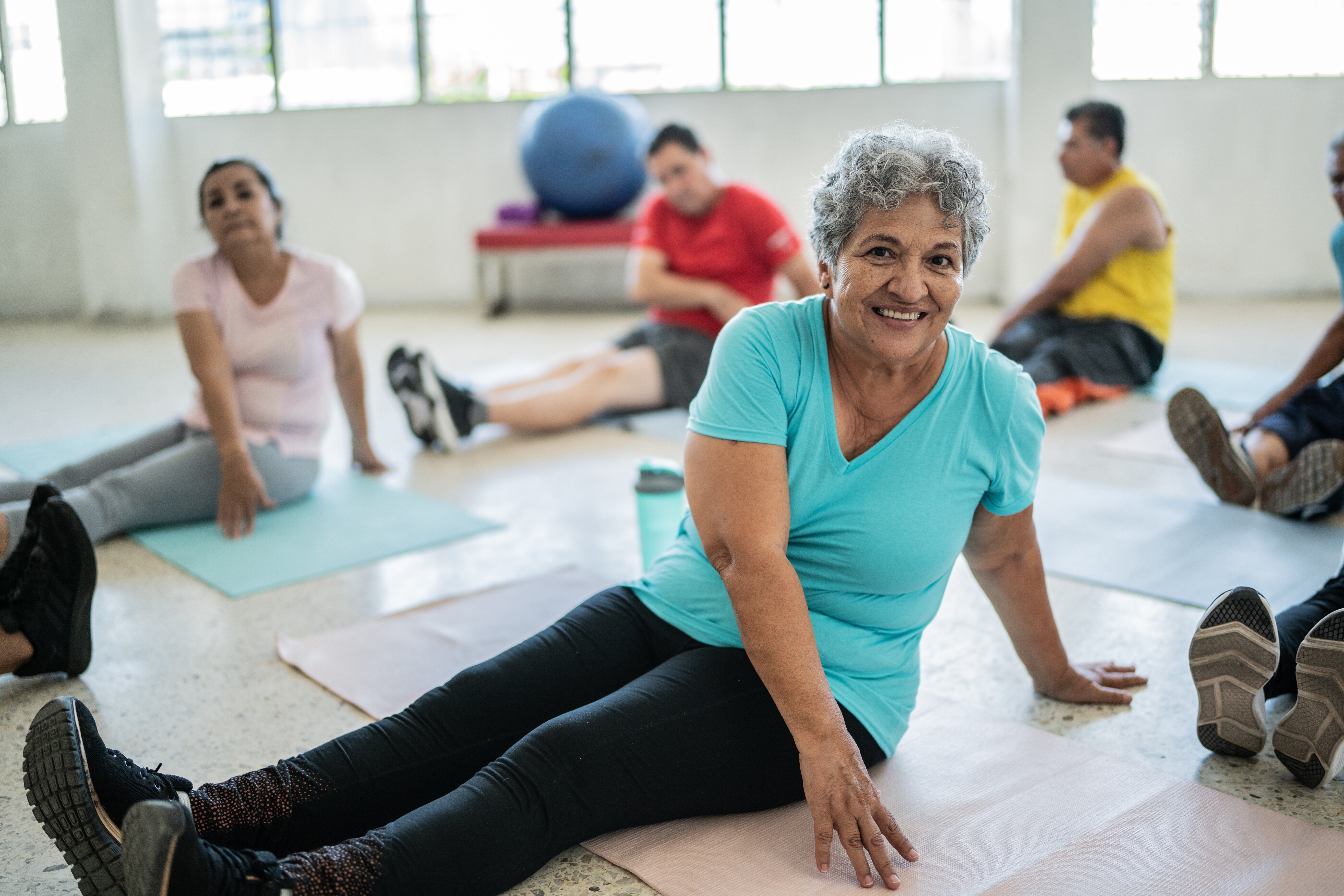 Portrait Of Senior Woman Stretching In A Yoga Class At A Studio