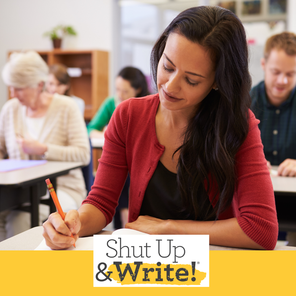 Adults sitting in a classroom writing documents by hand