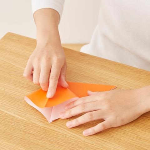 Up close of person's hands folding paper with precision in order to create something.