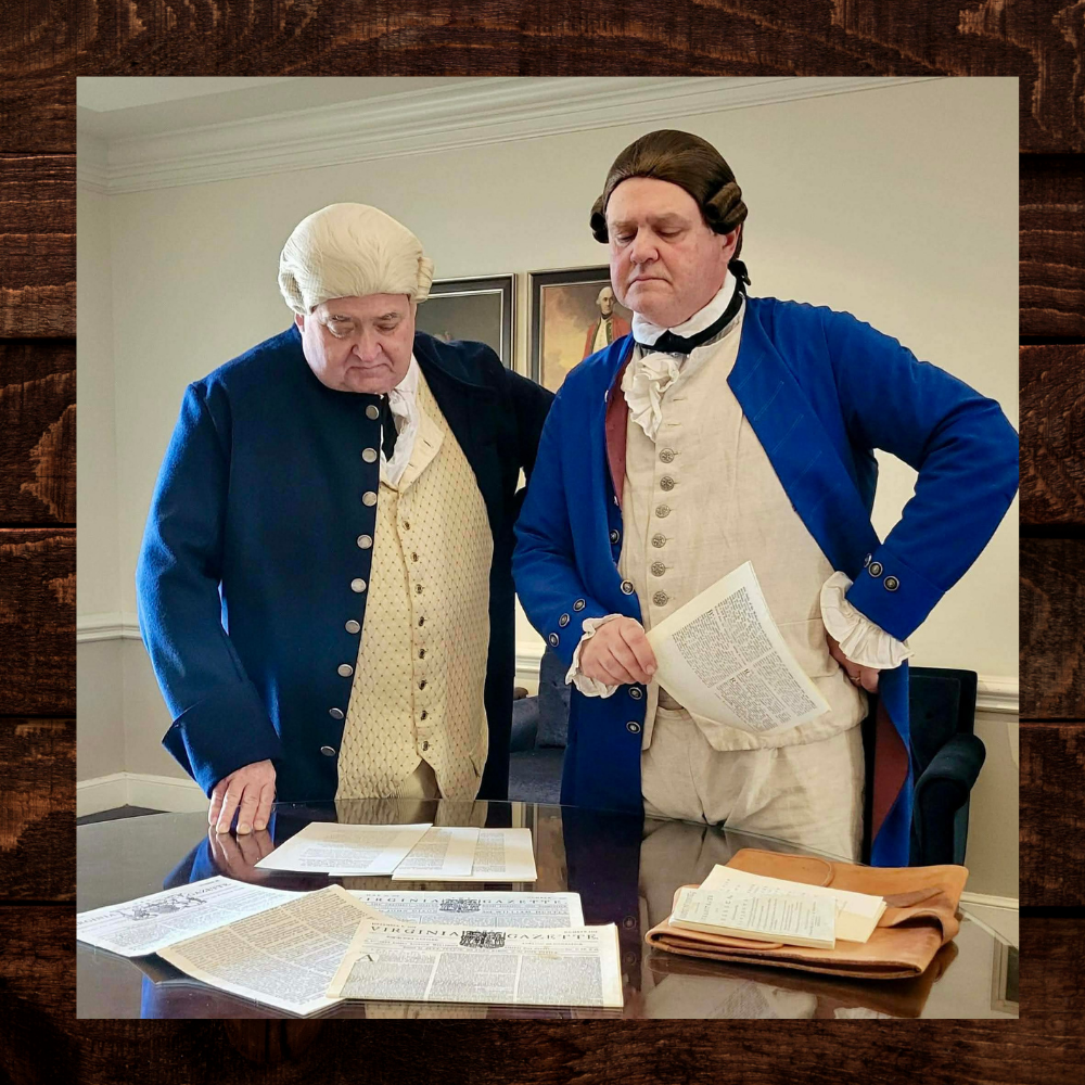 Two men in Colonial costumes read papers.