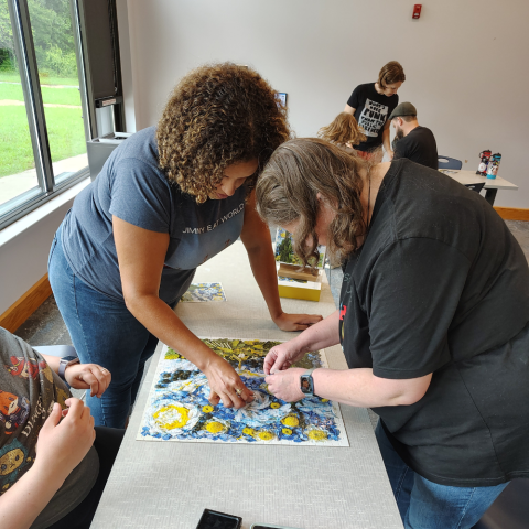 Groups of people assembling jigsaw puzzles. 