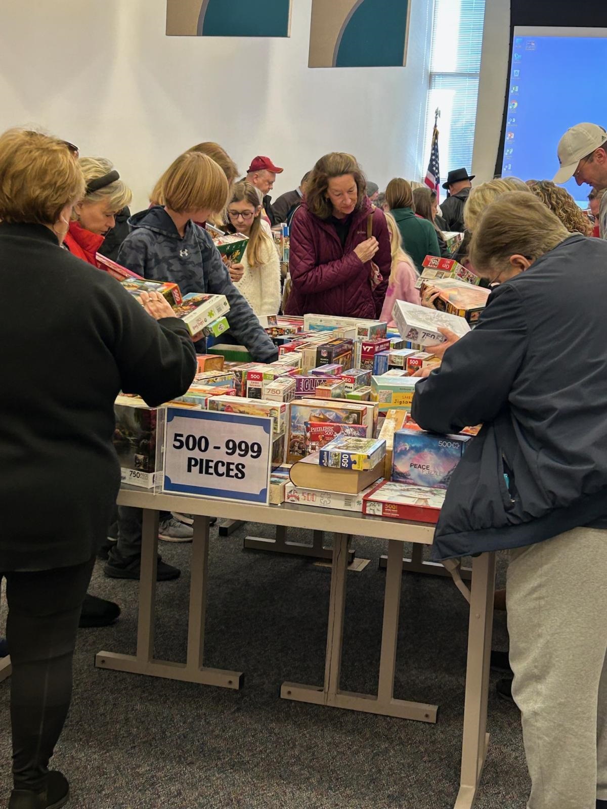 Large group of people at a table with several puzzles