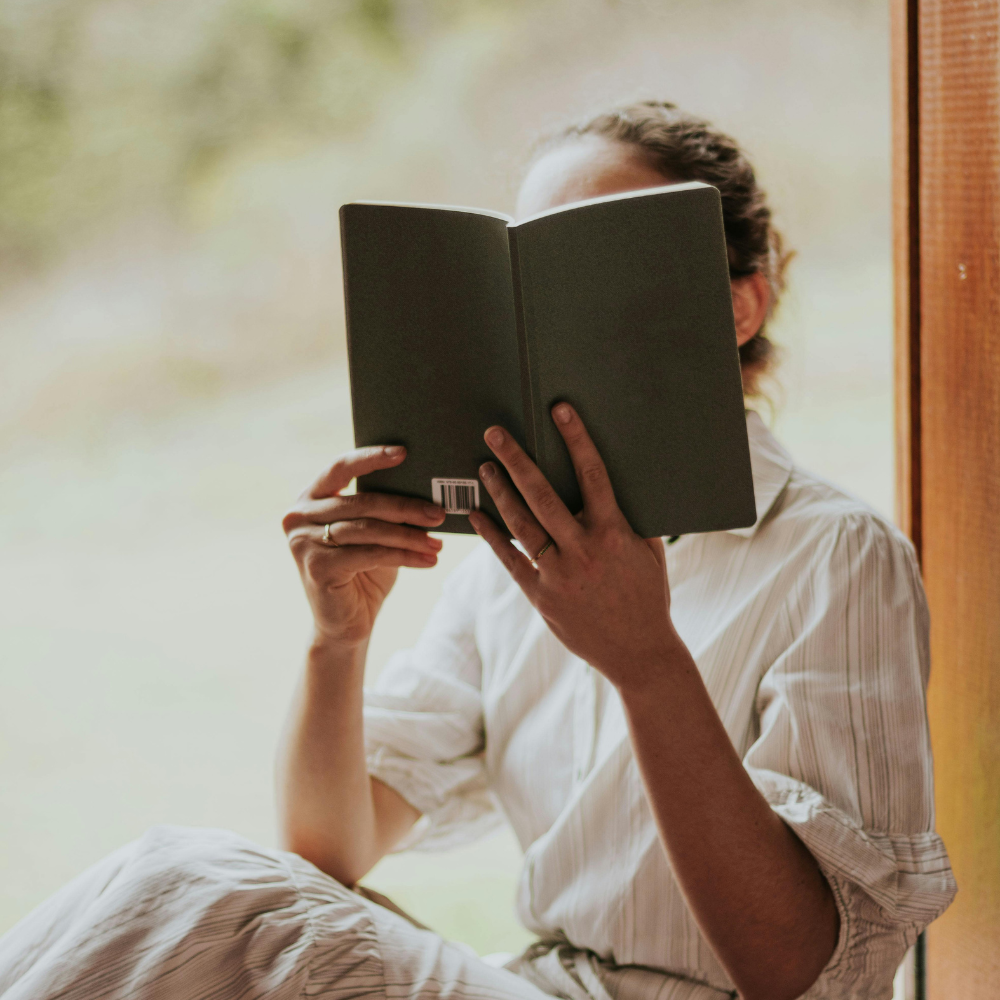 Woman sitting in a window reading a book
