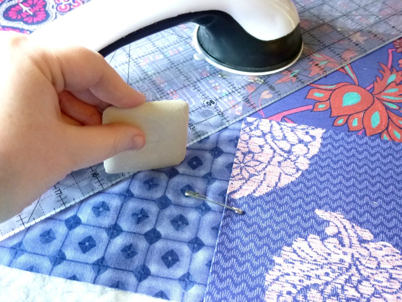 A hand is shown working on a quilt.