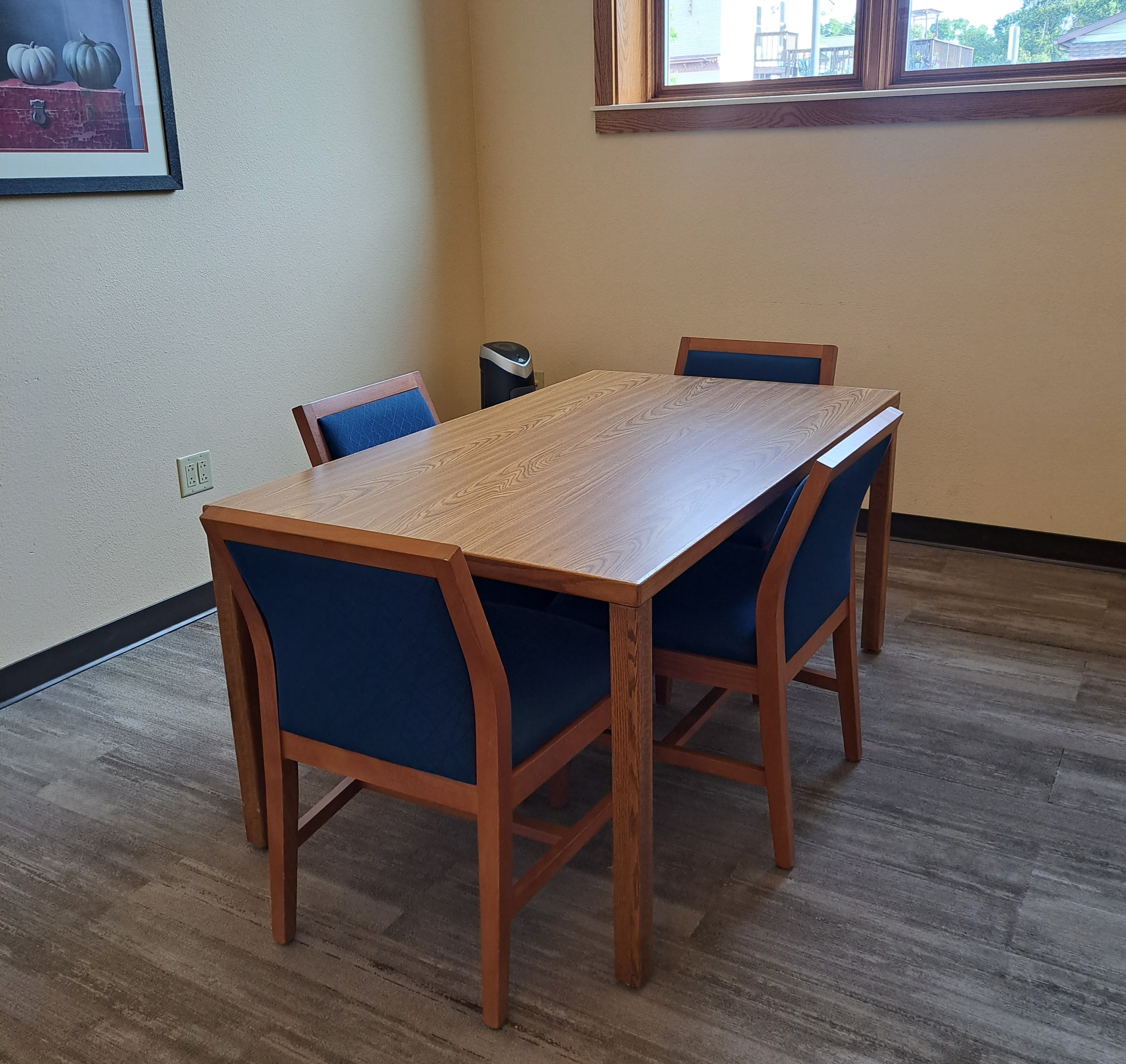 A study room with a table surrounded by 4 padded chairs and a HEPA air purifier in the corner.