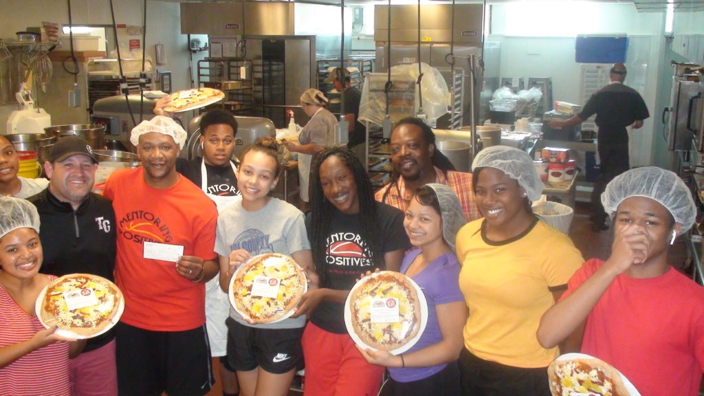 Picture of Mentoring Positives members holding pizza.