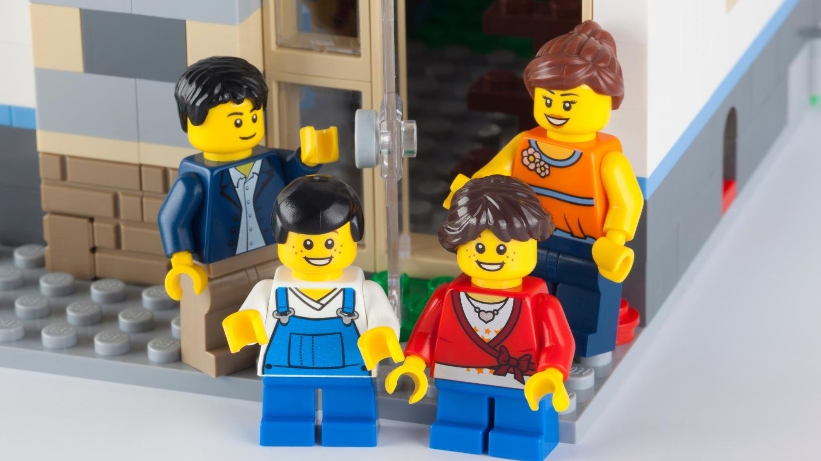 4 LEGO people by a LEGO building