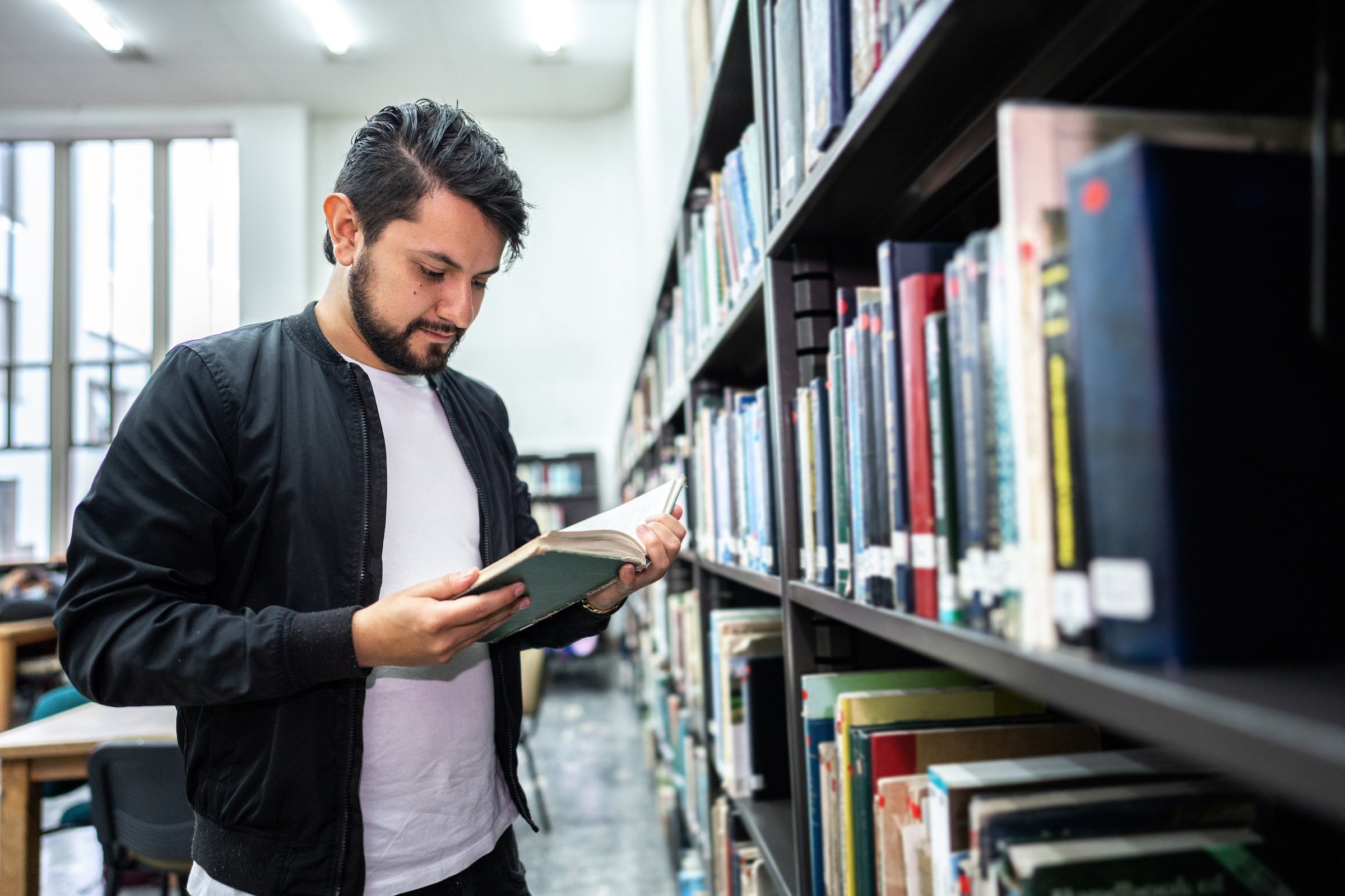 Male Adult Reading a Book in the Library