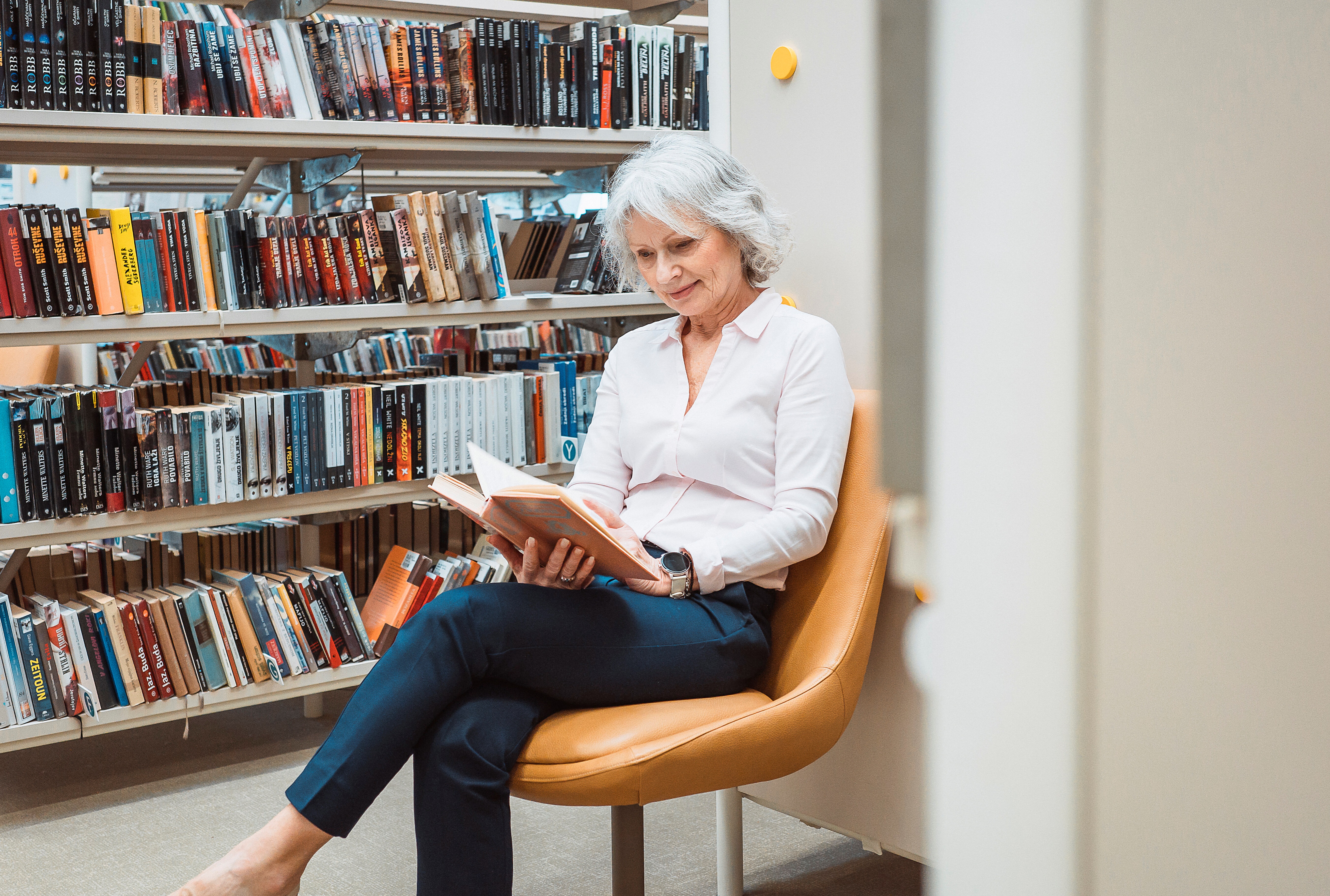 Senior Woman Reading A Book In The Library