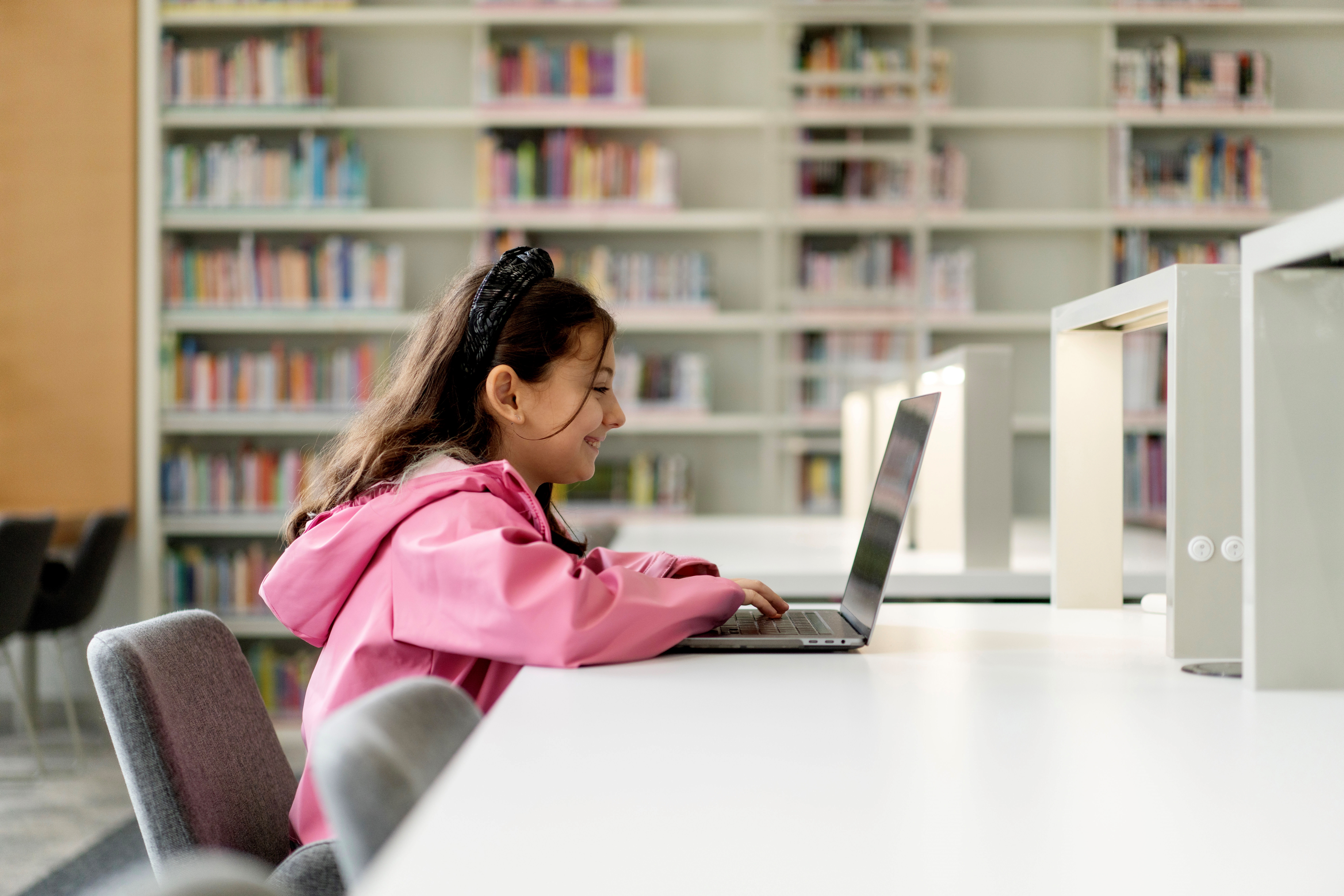 Little Girl Studying On Laptop In The Library