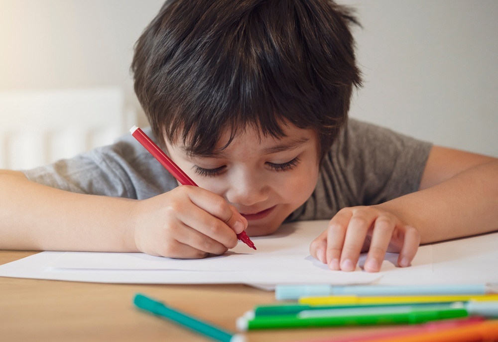 A young boy draws with markers.