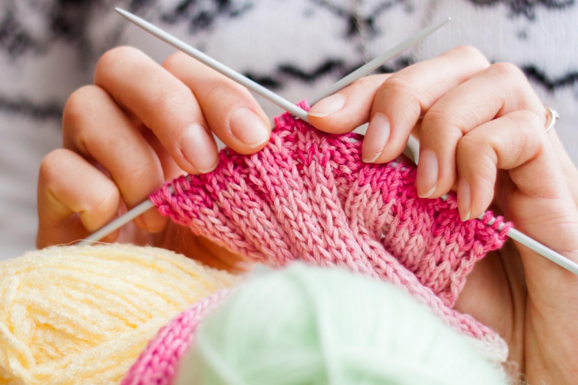 Close up of hands knitting with yarn.