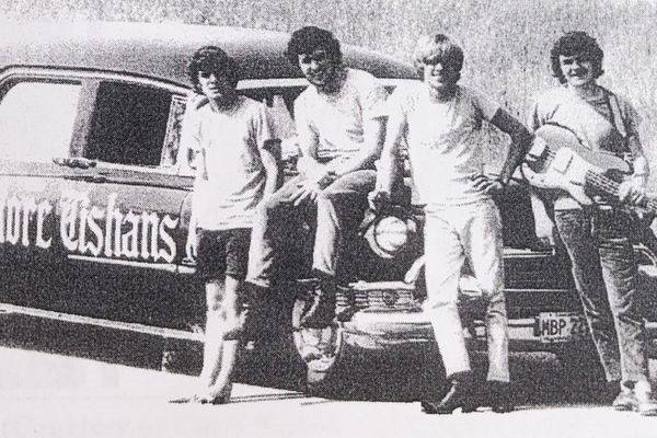 4 band members from The More-Tishans standing in front of their hearse