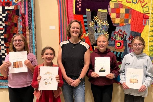 4 smiling youth writers with adult author Rebecca Ansari