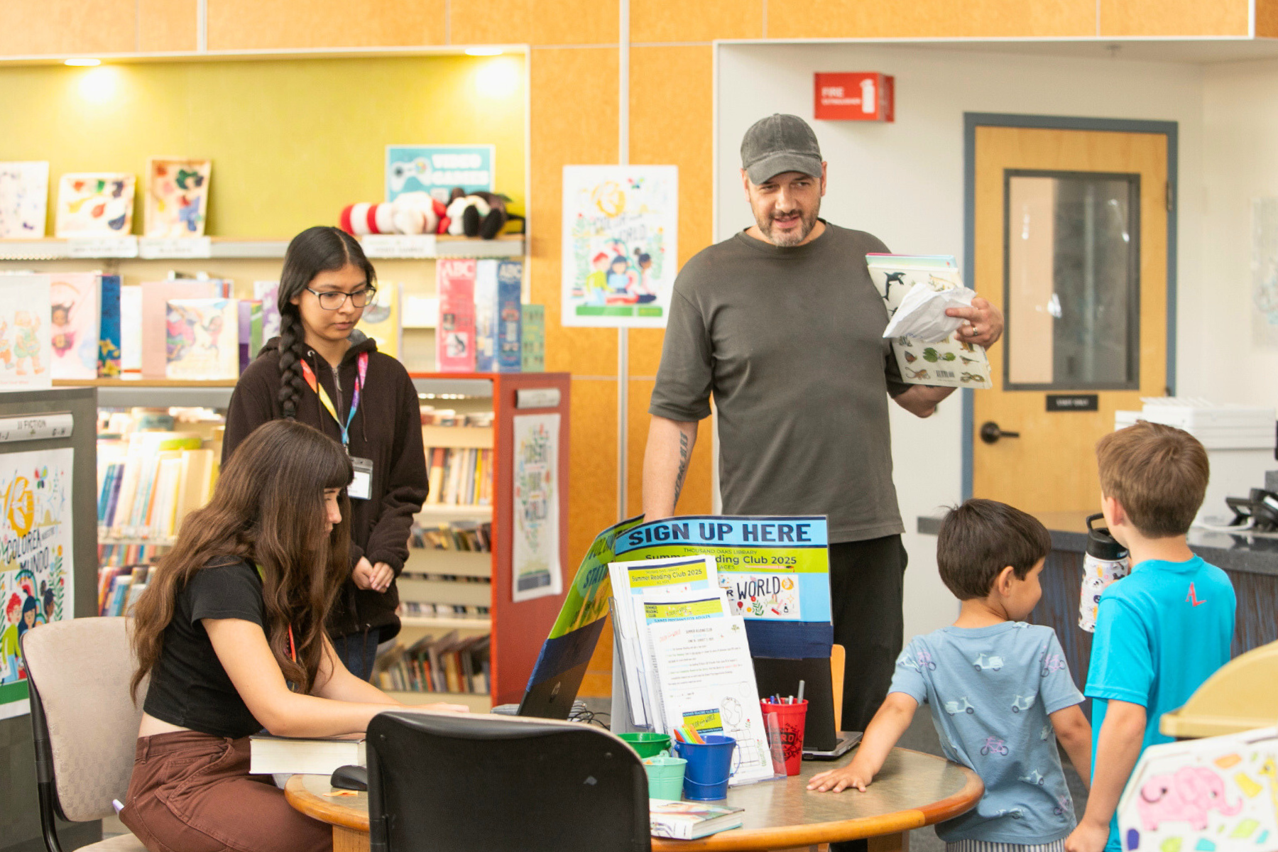 A parent and children signing up for Summer Reading!