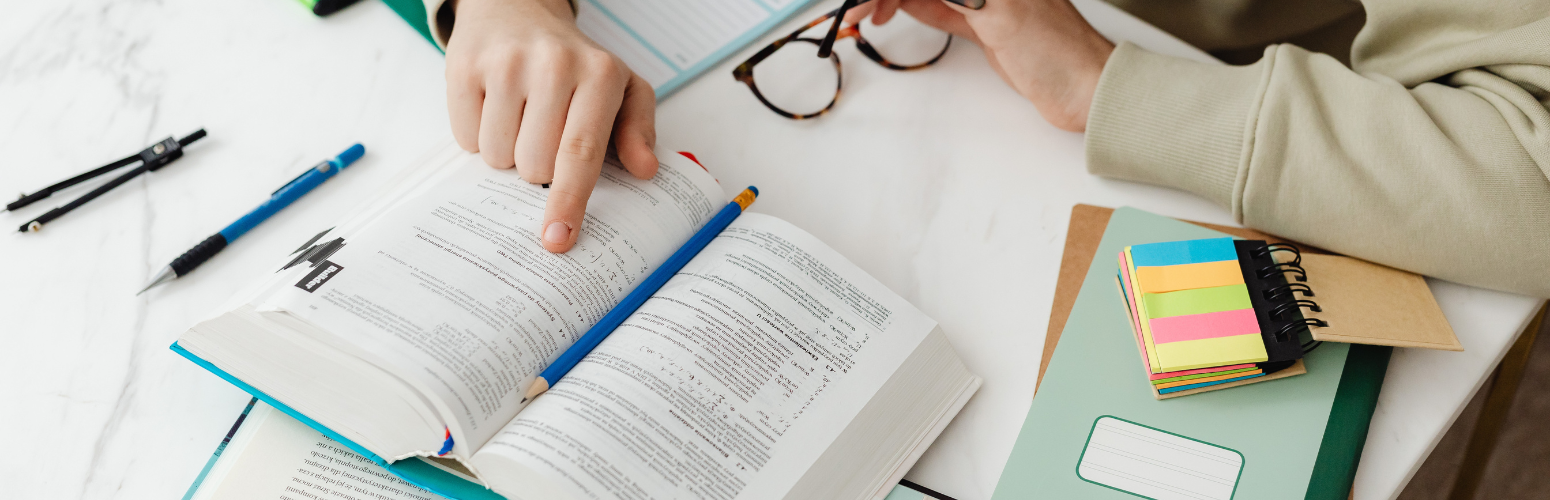 Photograph of an open book with studying supplies surrounding it.