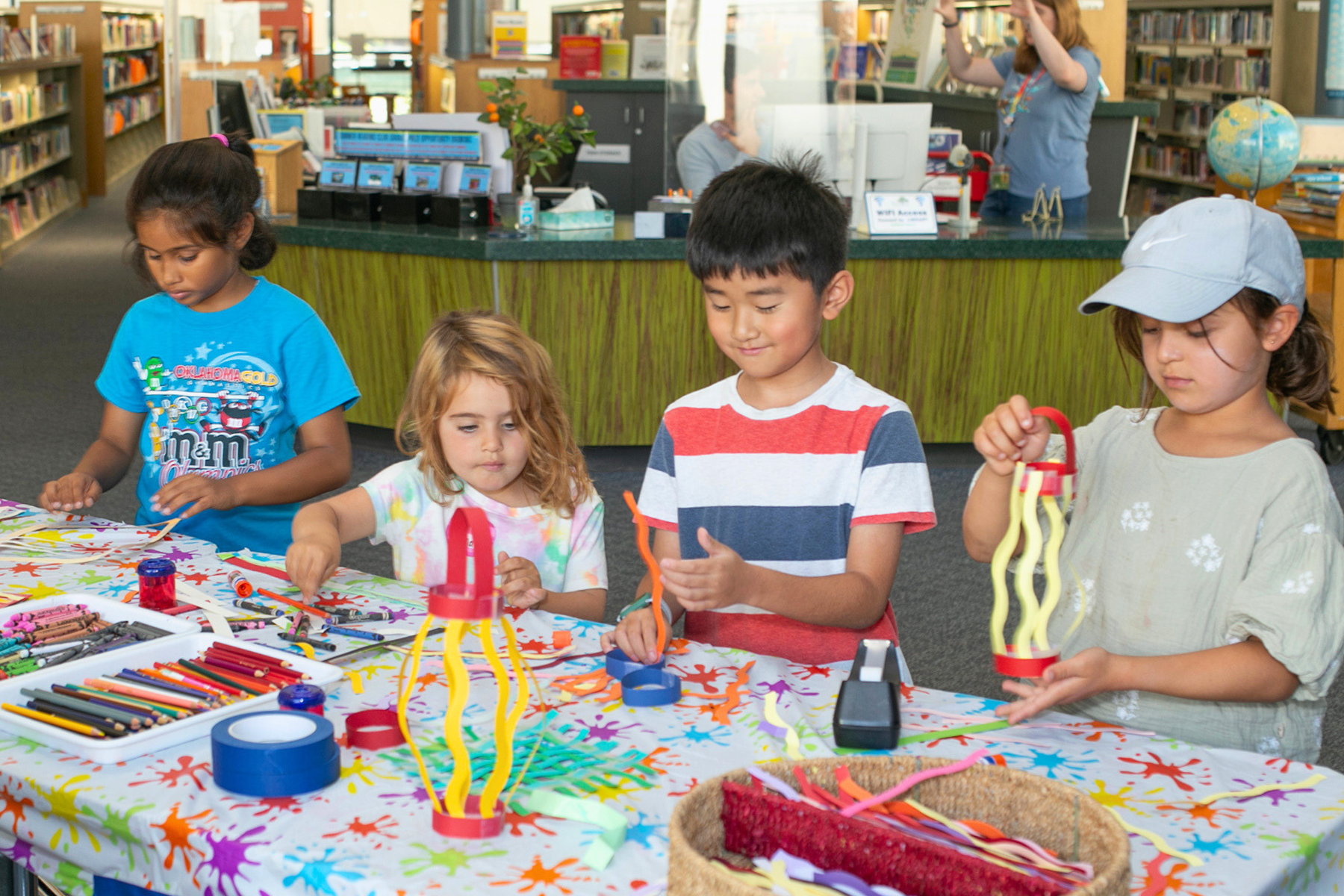 Four kids making crafts for summer reading club.