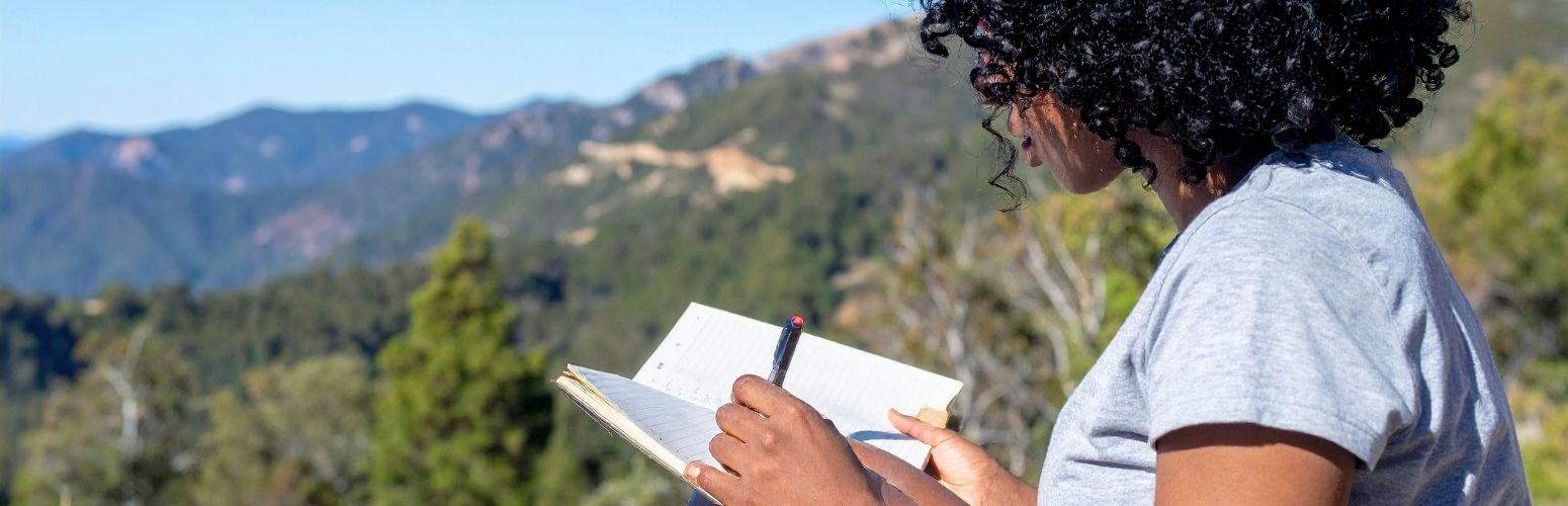 Woman writing in a notebook outside in nature. Woman writing in a notebook outside in nature.