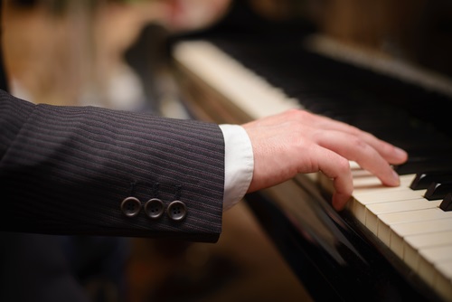 man's hands playing piano