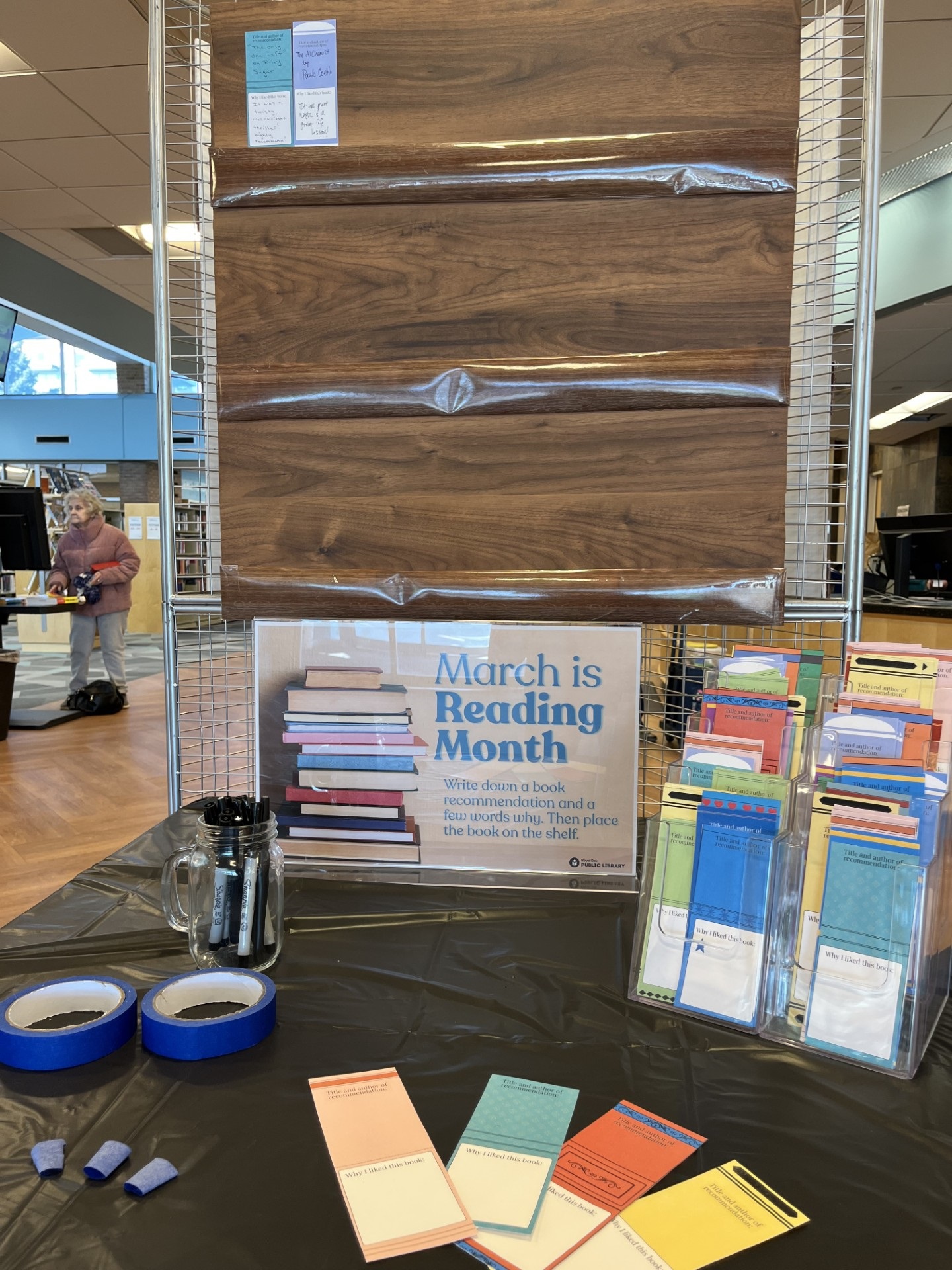 March is Reading Month, on a piece of paper designed like a book spine, write down a book recommendation and then tape it to the board decorated like bookshelves