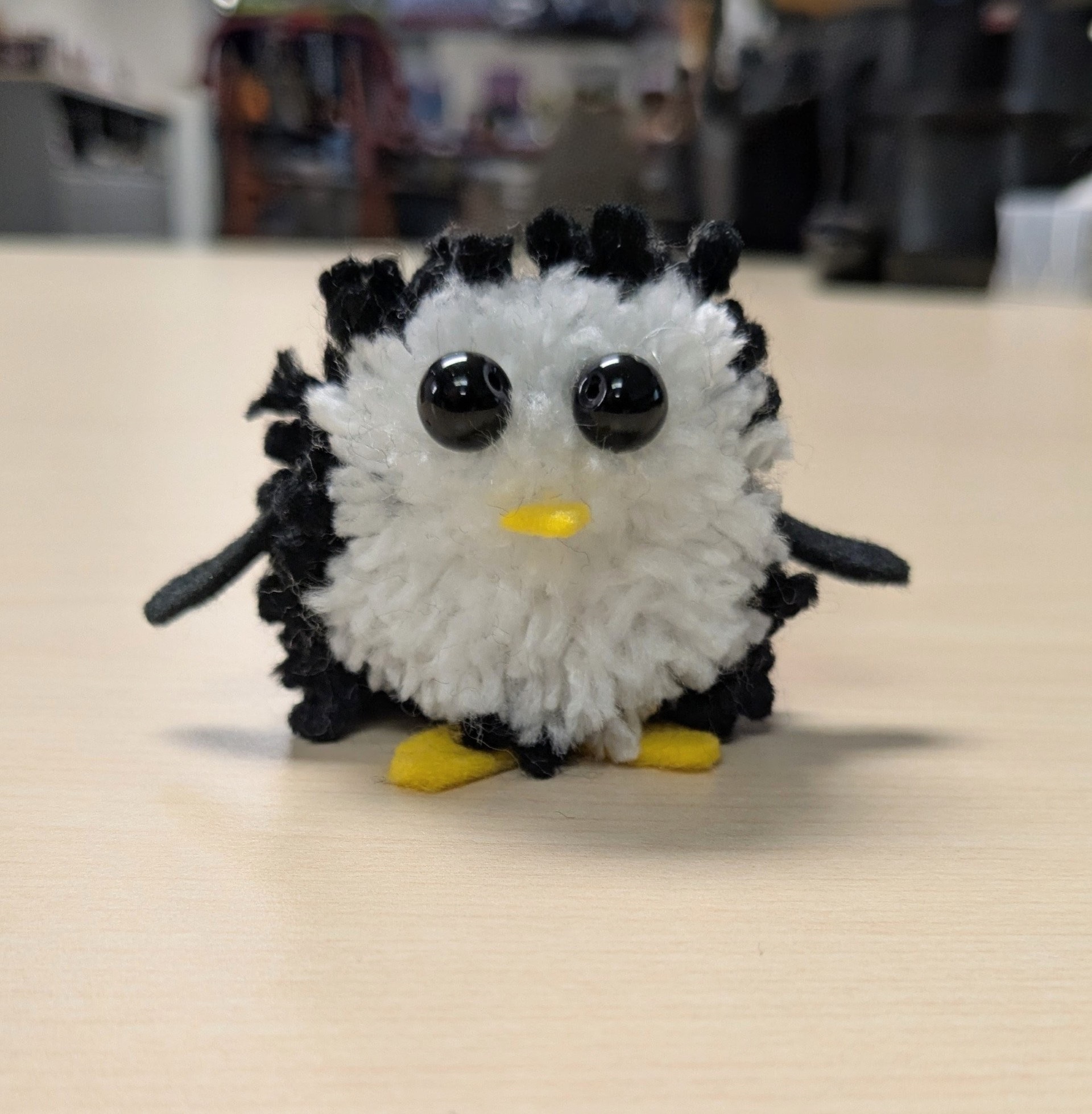Small round penguin made up of black and white yarn pom pom